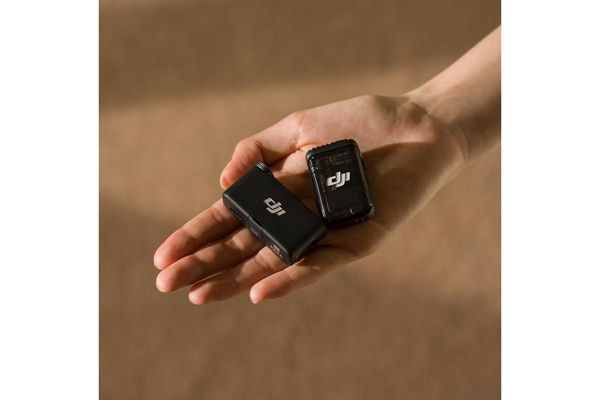 Kleines schwarzes drahtloses Mikrofon und Empfänger in einer Hand.