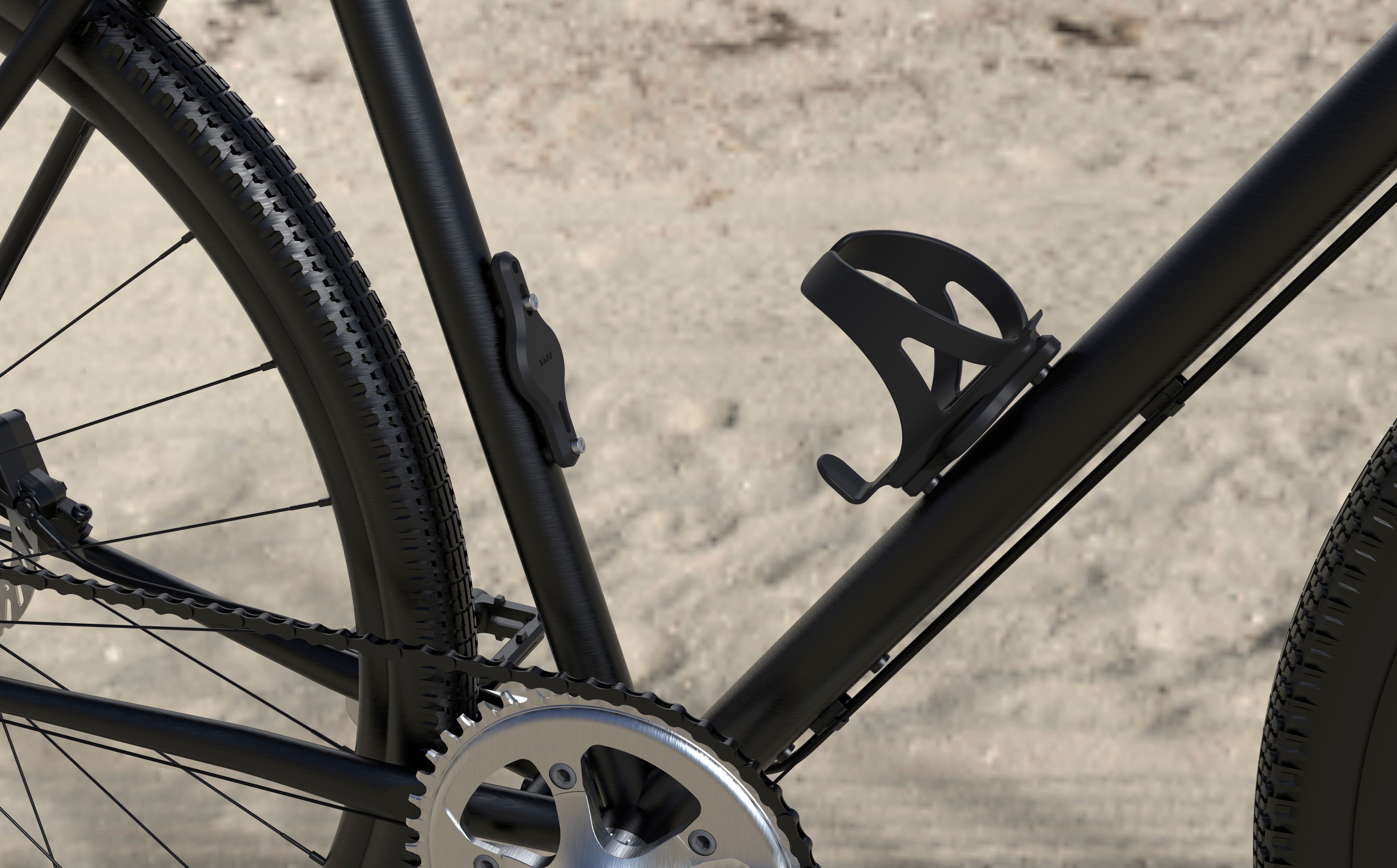 Schwarzes Fahrrad mit Kette und Flaschenhalter auf sandigem Untergrund.