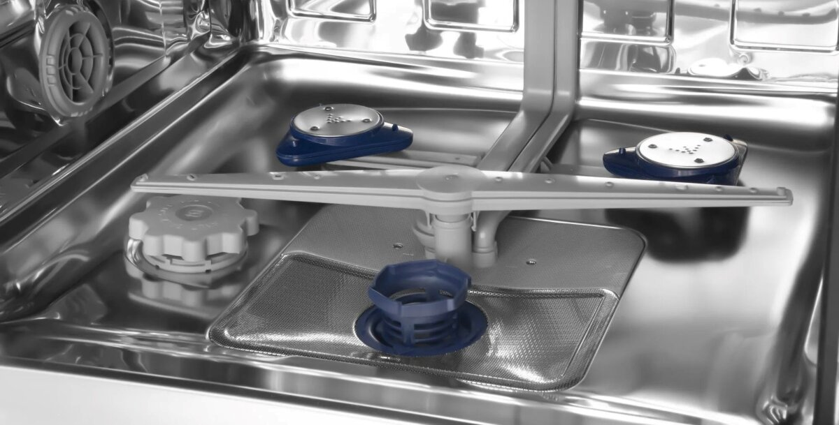 Wnętrze zmywarki ze stali nierdzewnej z niebieskimi ramionami natryskowymi i filtrem.