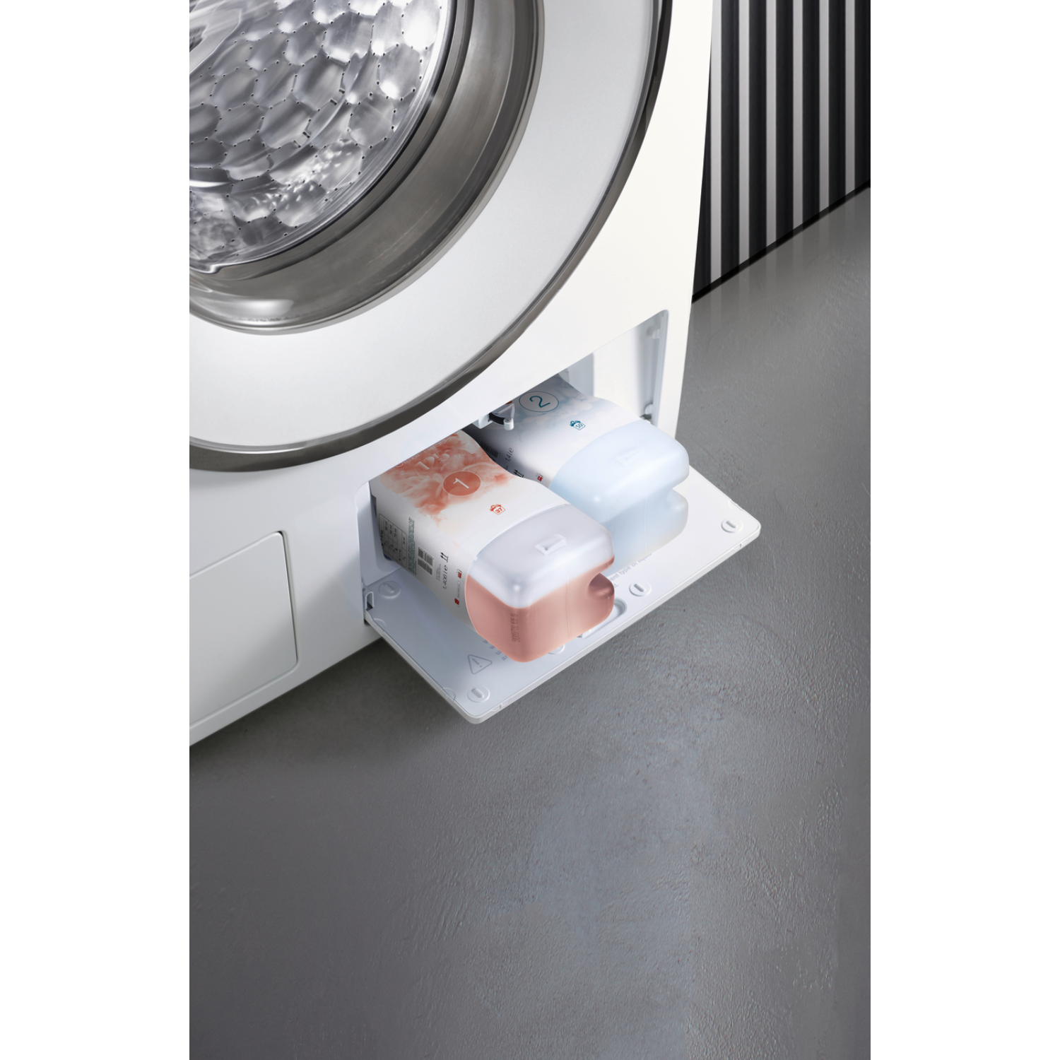 A close-up of a washing machine's detergent drawer, revealing compartments with detergent packs inside.