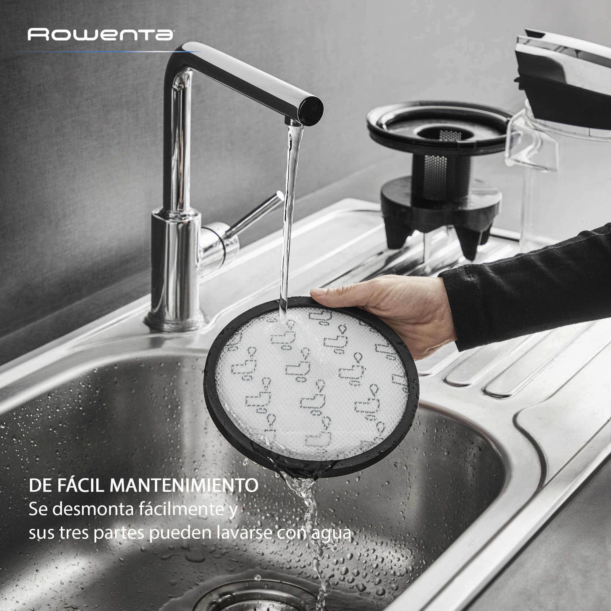 Mano lavando filtro en fregadero de cocina, texto en español.