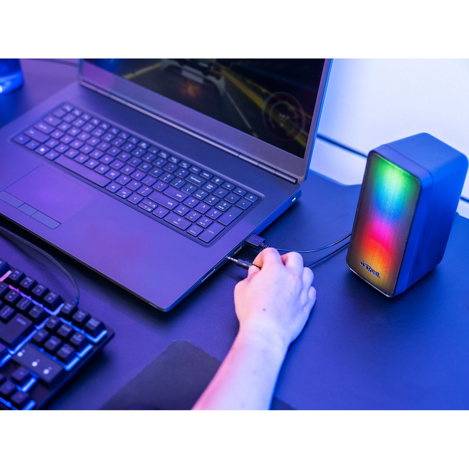 Ordinateur portable connecté à un haut-parleur avec affichage lumineux coloré sur un bureau.