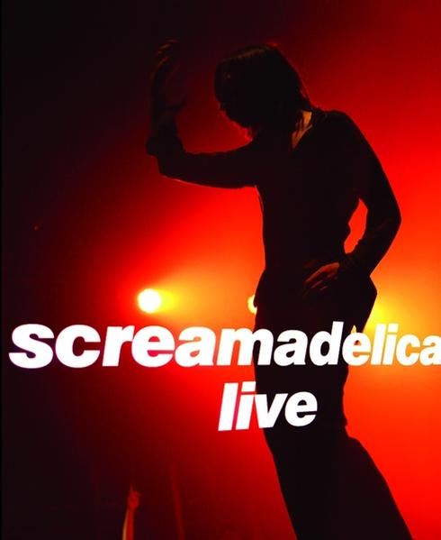 Egy személy sziluettje a színpadon, piros fényekkel és a 'Screamadelica Live' felirattal.