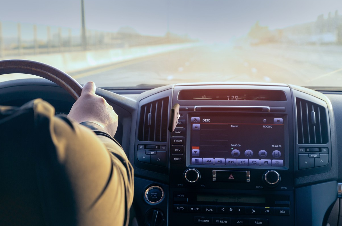 Main du conducteur sur le volant, vue du tableau de bord et de la route.