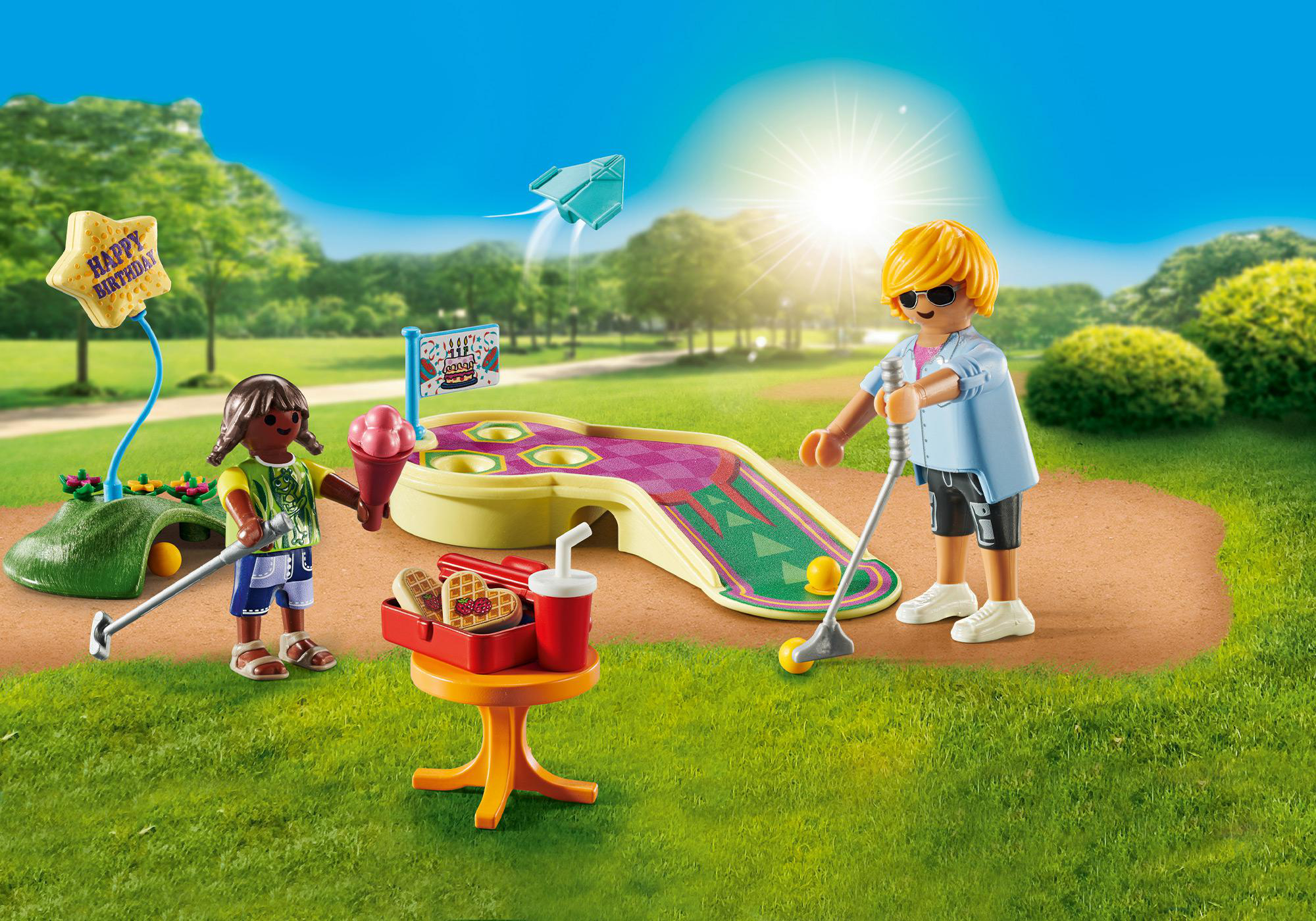 Kinder spielen Minigolf mit Geburtstagskuchen und Snacks auf einem Tisch.