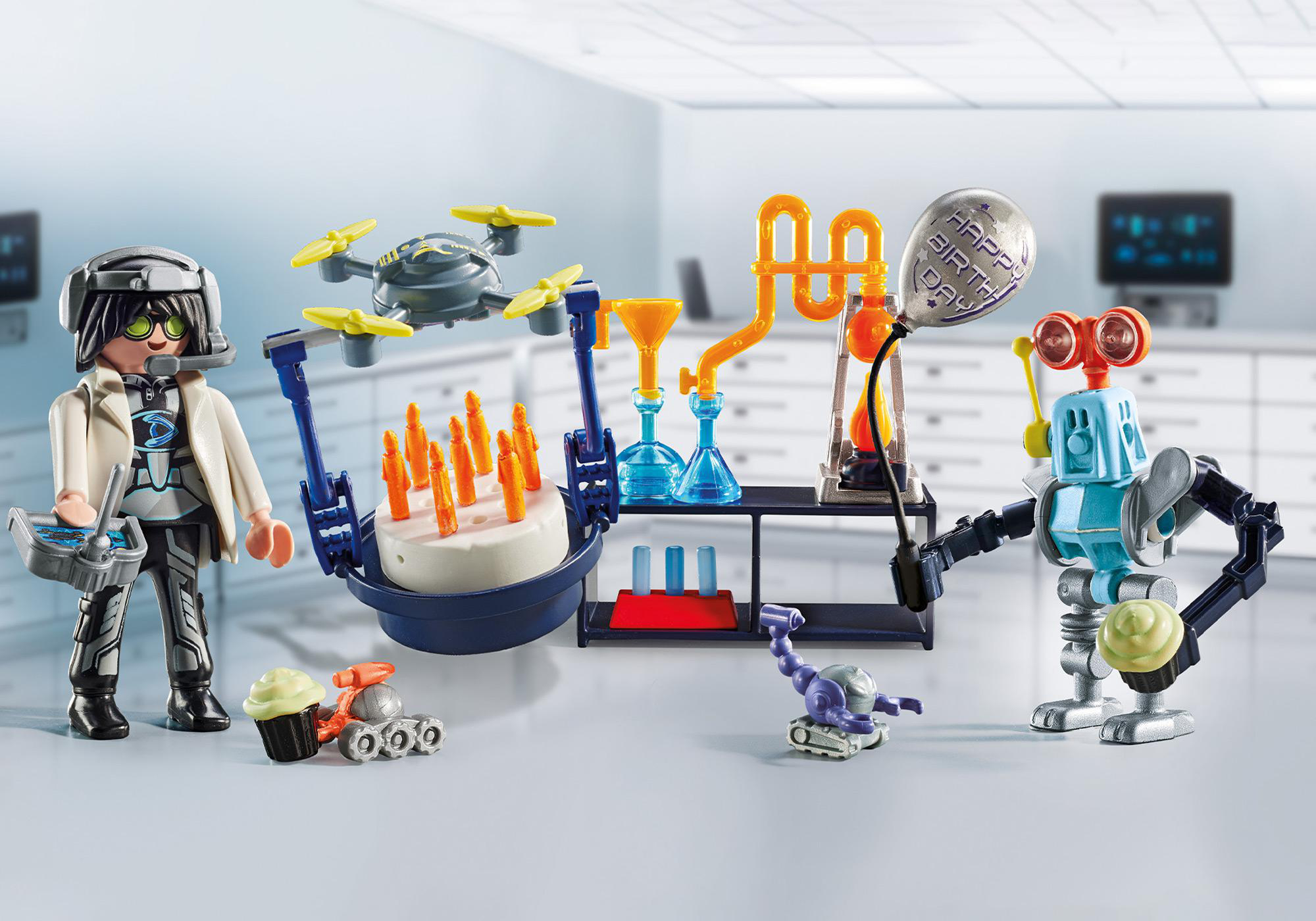 Eine Playmobil-Szene mit einem Wissenschaftler, einem Roboter, einem Kuchen und Laborgeräten.