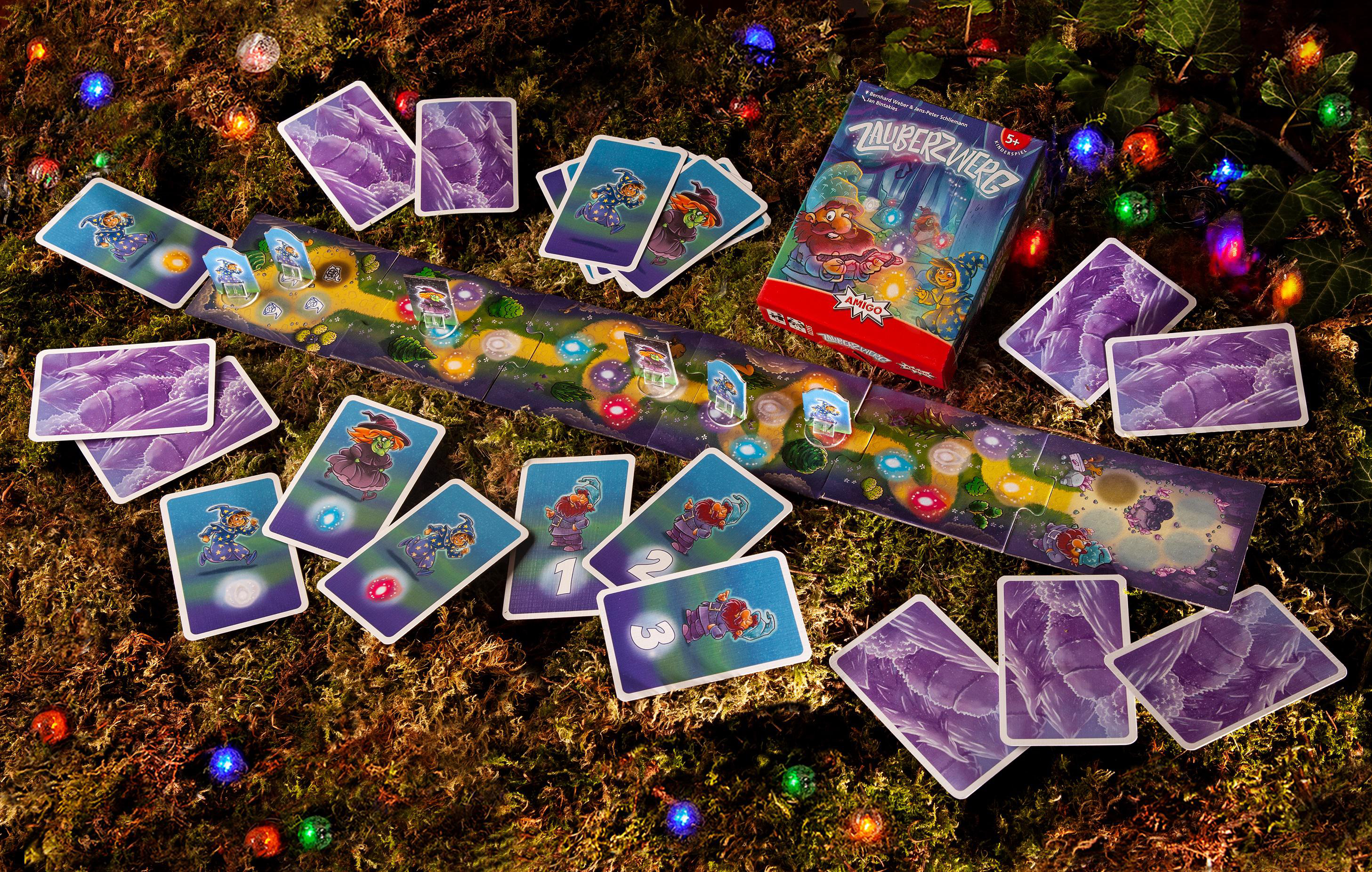 Ein Brettspiel-Setup auf Moos, mit Karten und einer Box.
