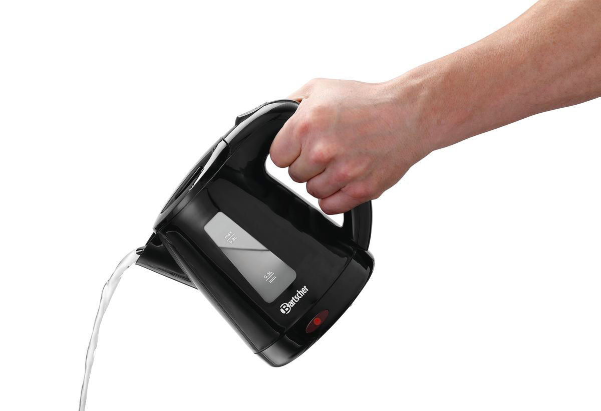 Eine Hand gießt Wasser aus einem schwarzen Wasserkocher vor weißem Hintergrund.