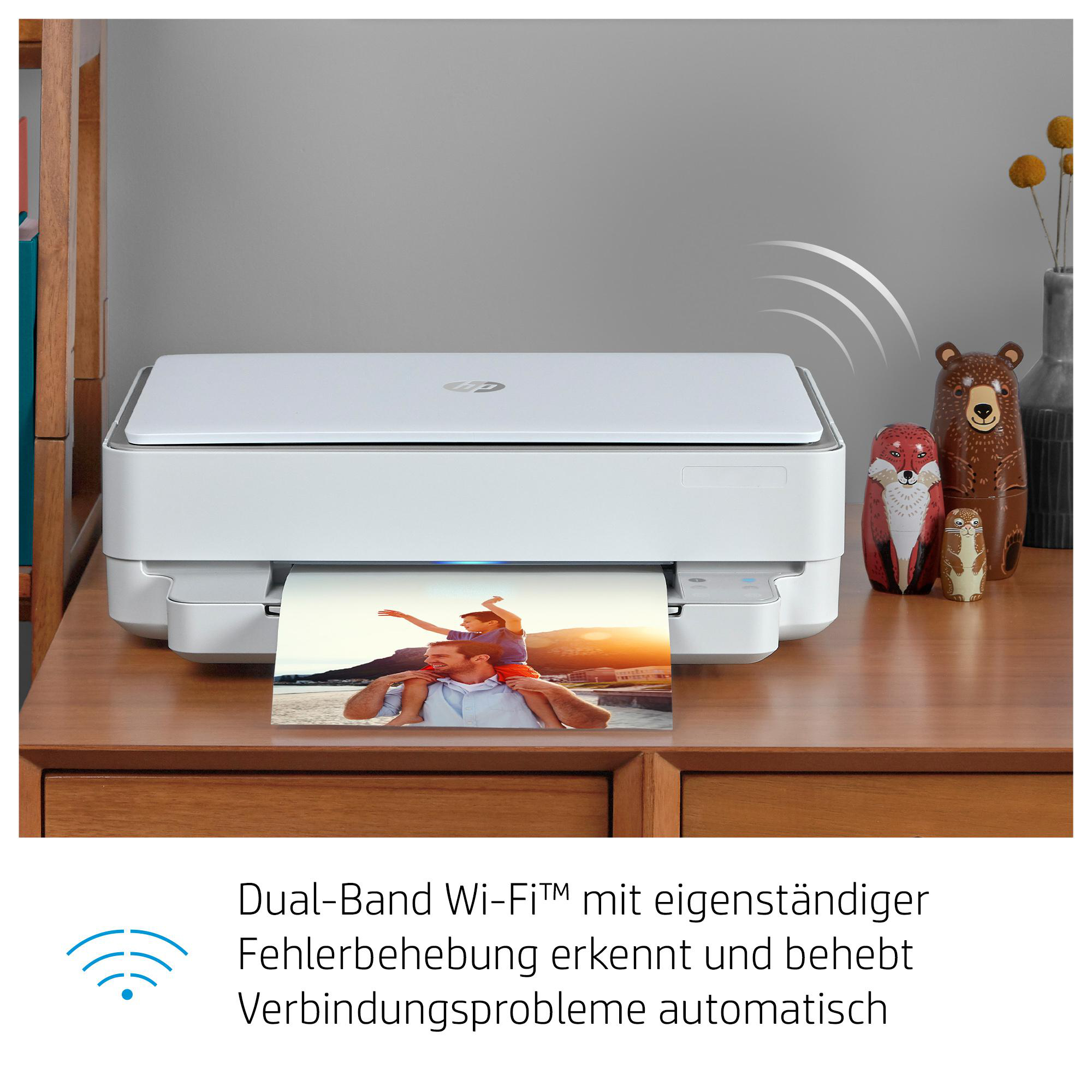 Weißer Drucker druckt ein Foto, mit zwei hölzernen Bärenfiguren und einer Fuchsfigur.