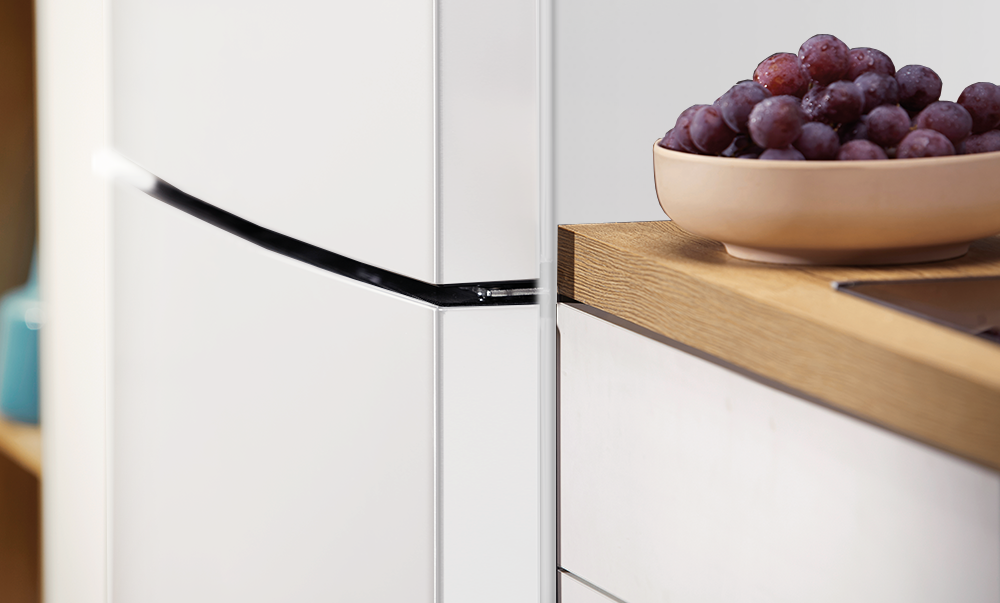 Zbliżenie białych szafek kuchennych z miską winogron na drewnianym blacie.