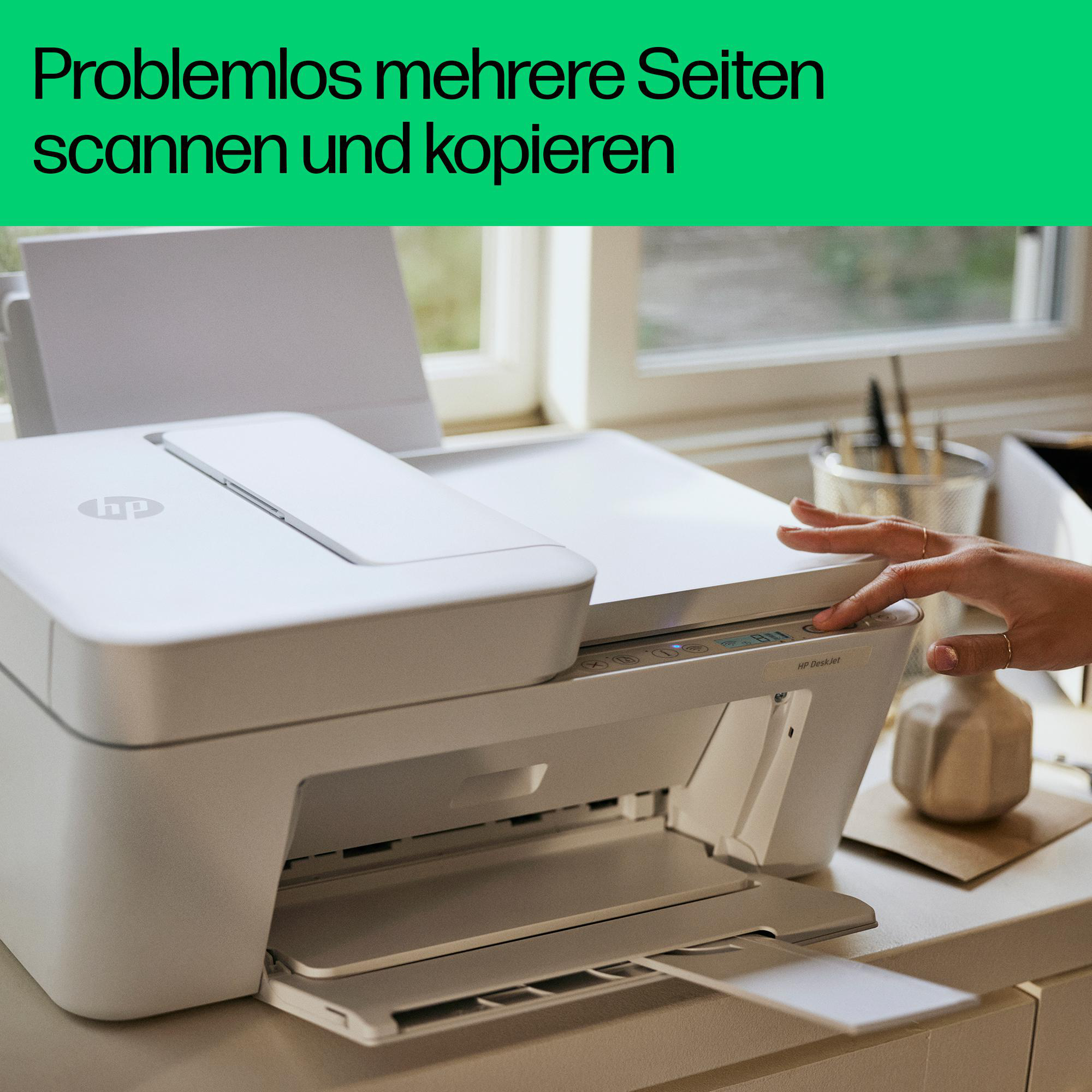 Die Hand einer Frau drückt eine Taste auf einem weißen Drucker. Im Hintergrund befindet sich ein Fenster.