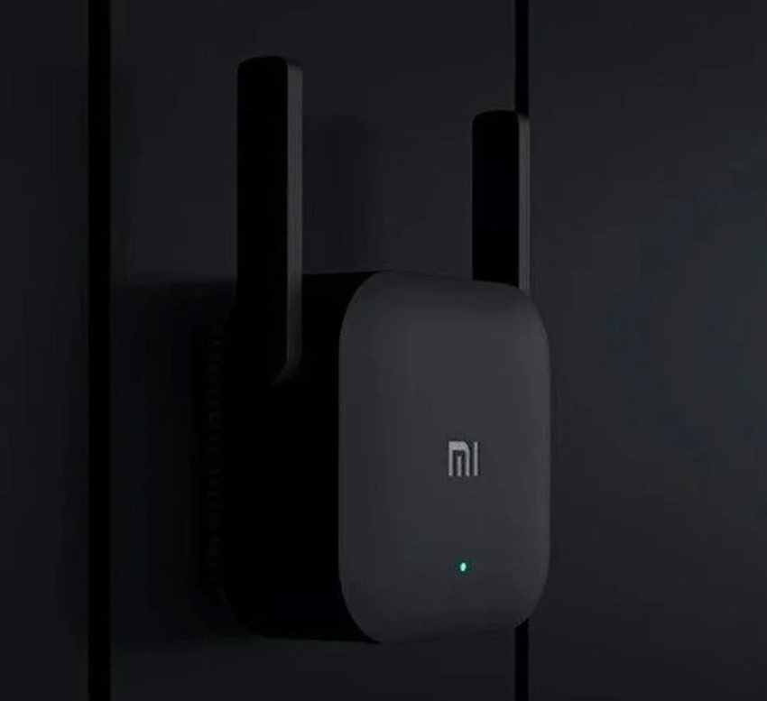 İki antenli, karanlık bir duvara monte edilmiş siyah bir Wi-Fi genişletici. Yeşil bir ışık yanıyor.