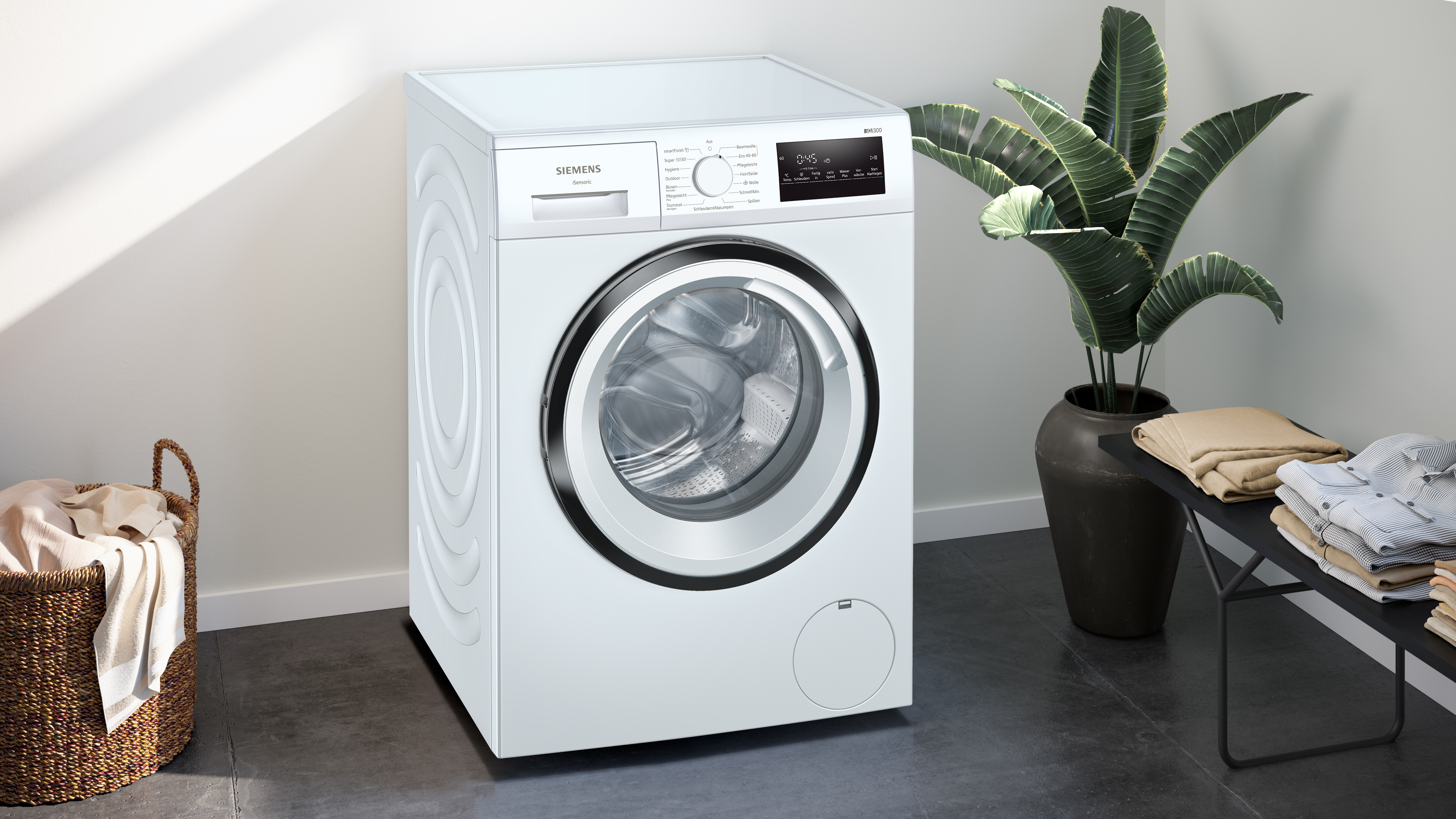 Weiße Siemens Waschmaschine, mit einem Korb und Pflanzen im Hintergrund.