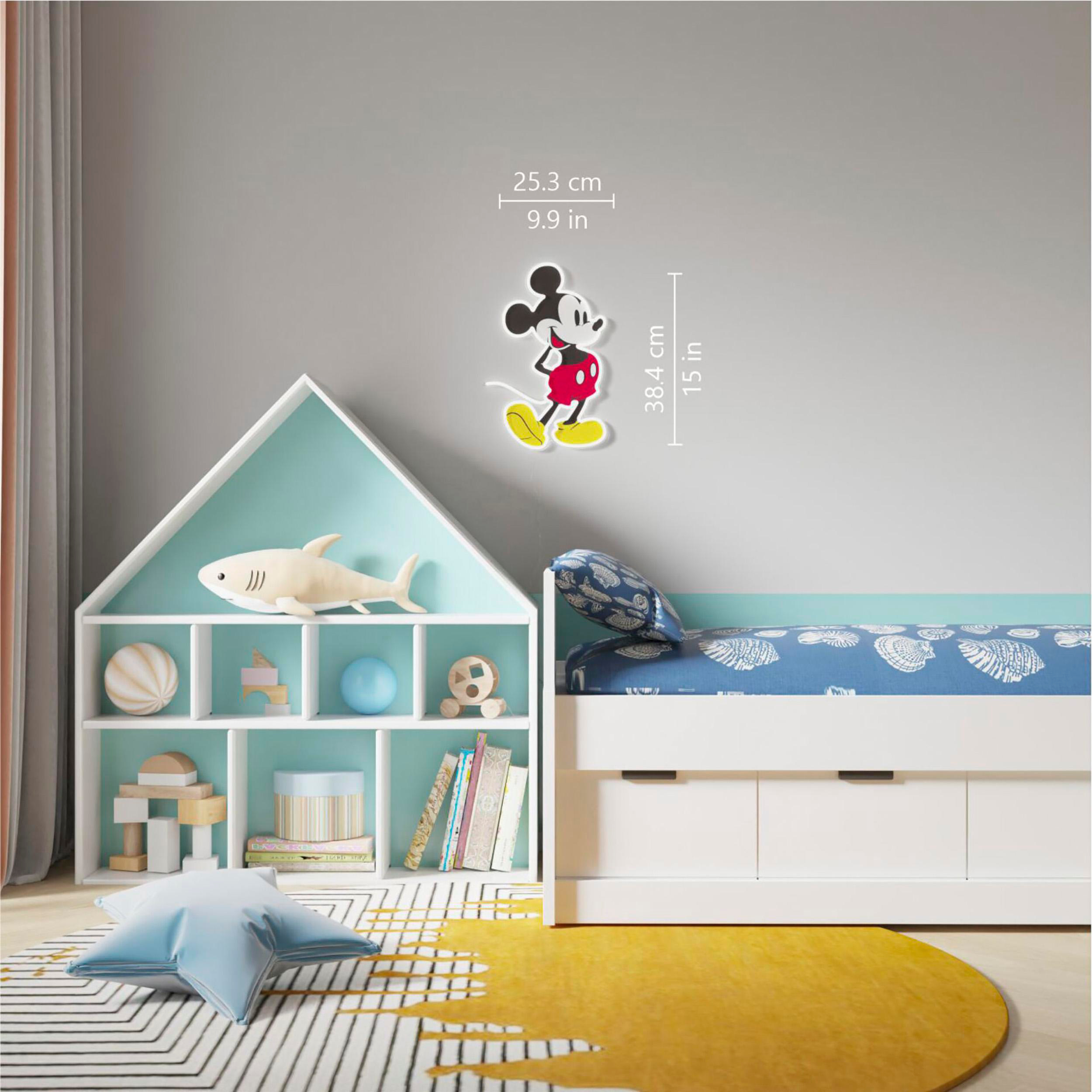 Mickey Mouse Aufkleber an einer grauen Wand, neben einem Bücherregal und einem Bett. Ein gelber Teppich liegt auf dem Boden.