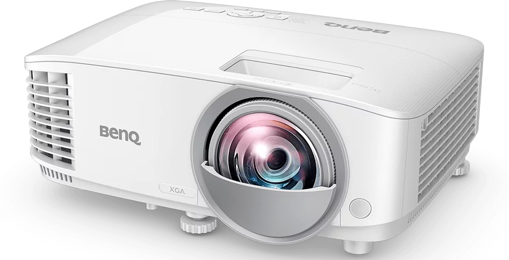 Fehér BenQ projektor fekete felületen. Lencse és szellőzőnyílások láthatók. Márkanév felül.