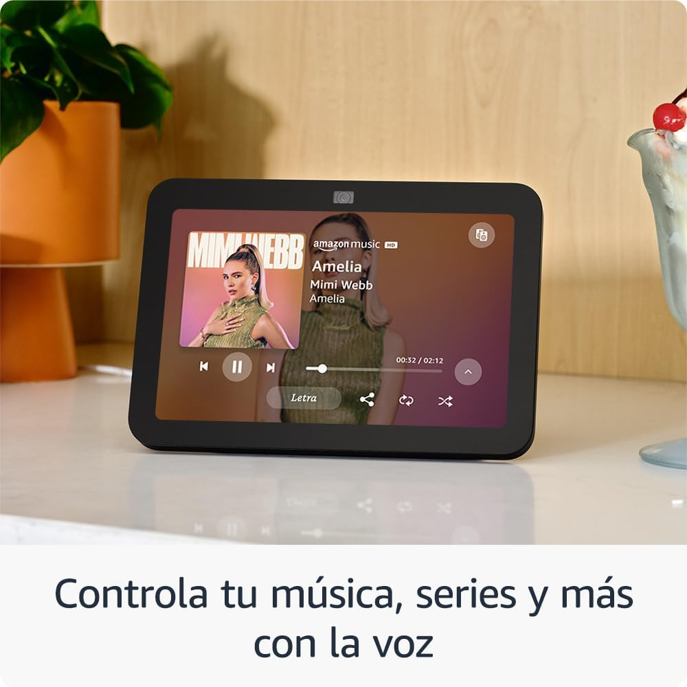 Tableta negra muestra una mujer y controles de música. Una planta y bebida en el fondo.