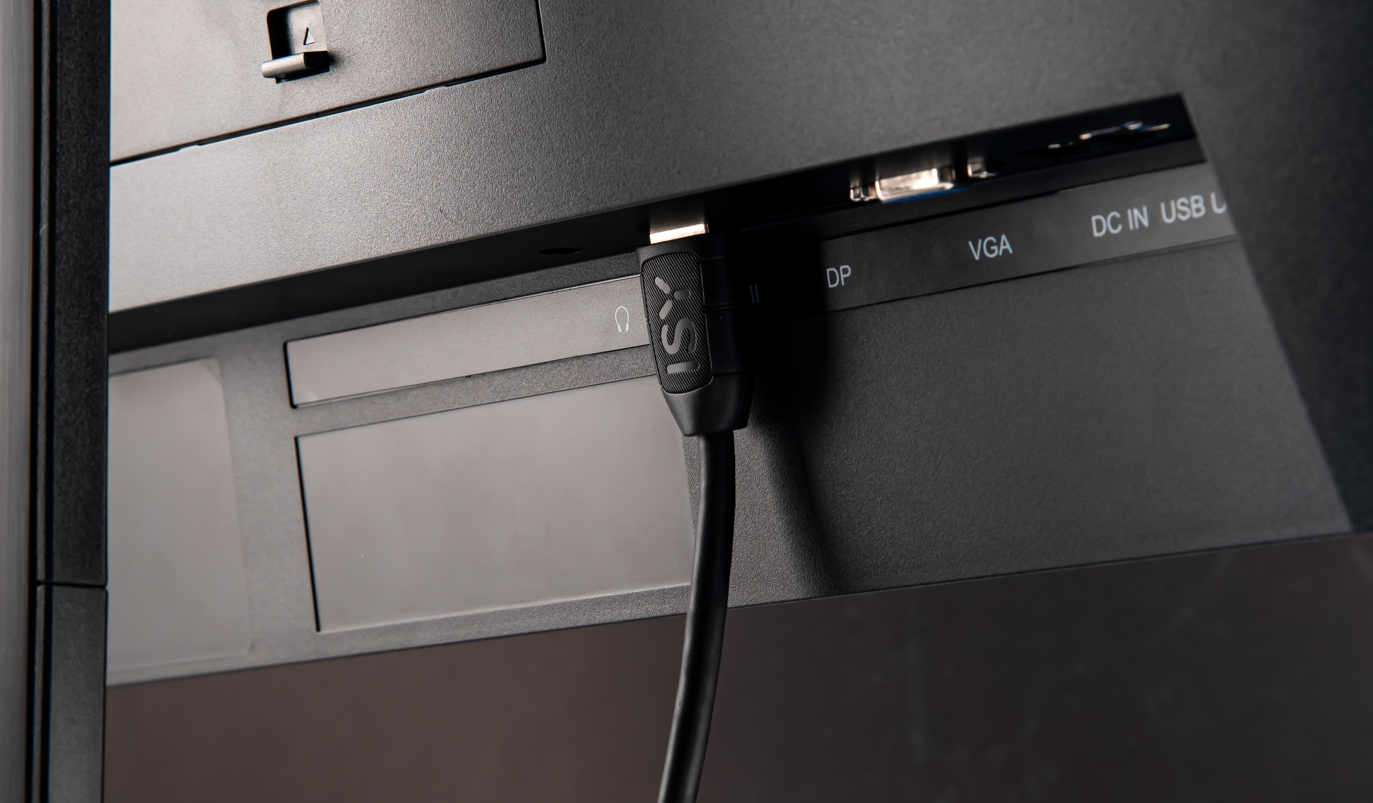 Gros plan de l'arrière d'un moniteur avec ports HDMI, DP, VGA et USB. Câble noir branché.