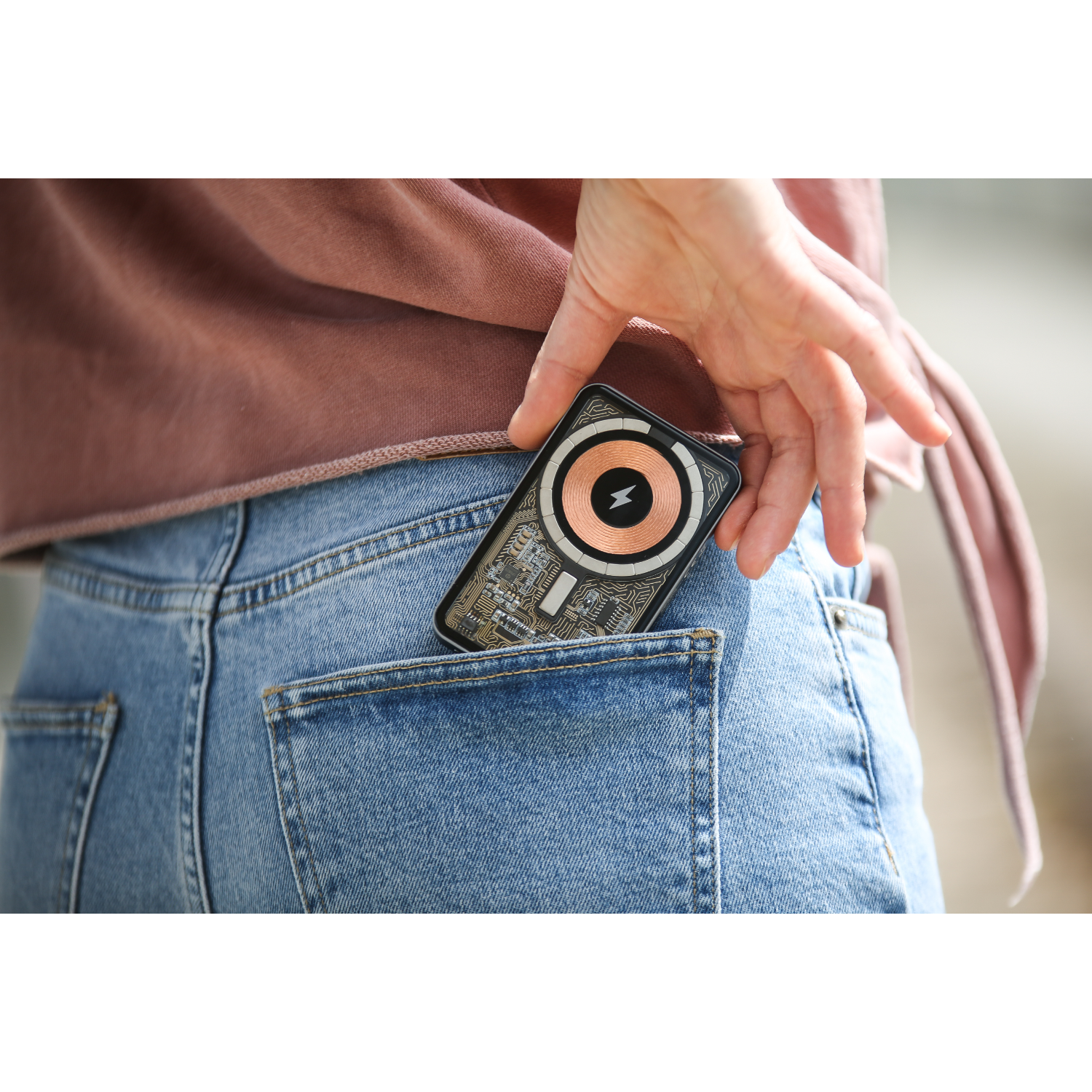A hand putting a black device into a blue jeans pocket.
