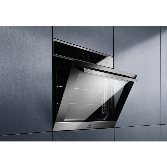 Un horno Electrolux con la puerta abierta. El horno está empotrado en una pared gris.