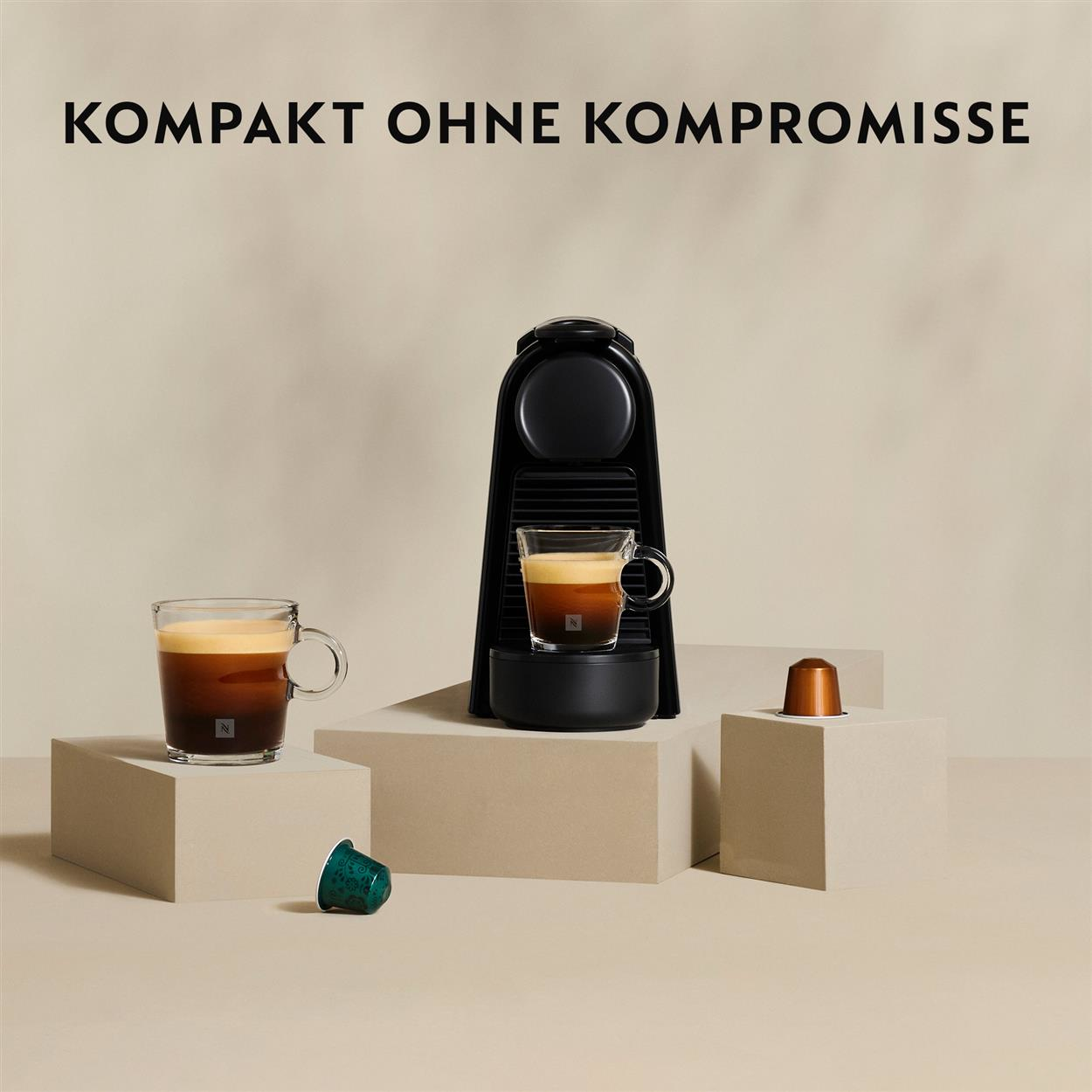 Kaffeemaschine mit zwei Kaffeetassen und Kaffeepads auf beigem Untergrund.