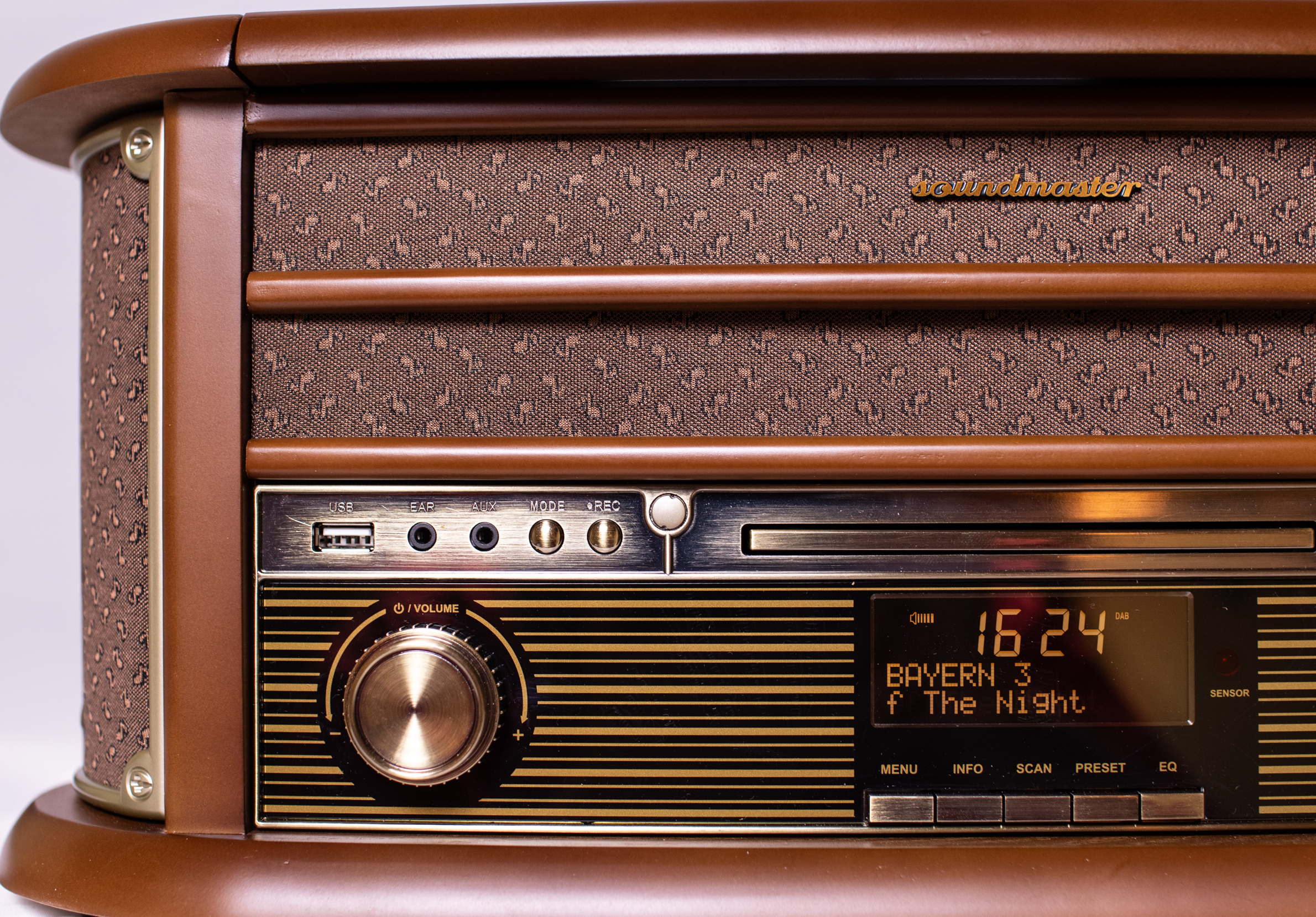 Lecteur radio rétro. Marron avec des accents dorés. L'écran affiche l'heure et les infos radio.