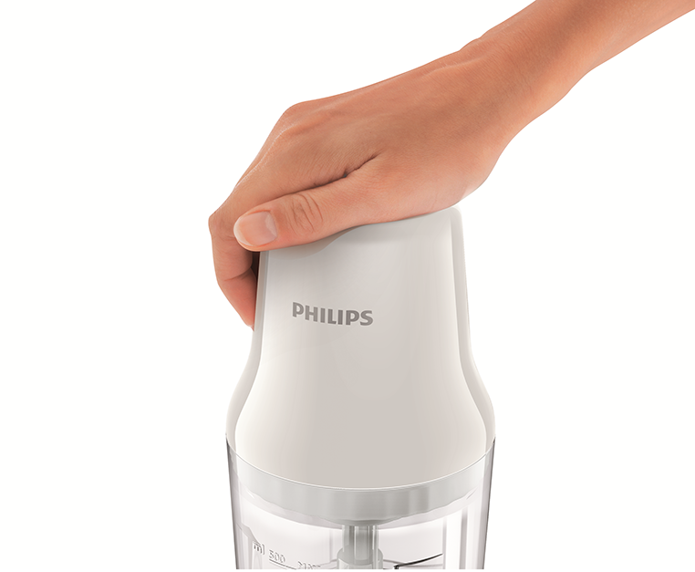Kéz egy fehér és átlátszó Philips konyhai robotgépet tart. A Philips logó látható.
