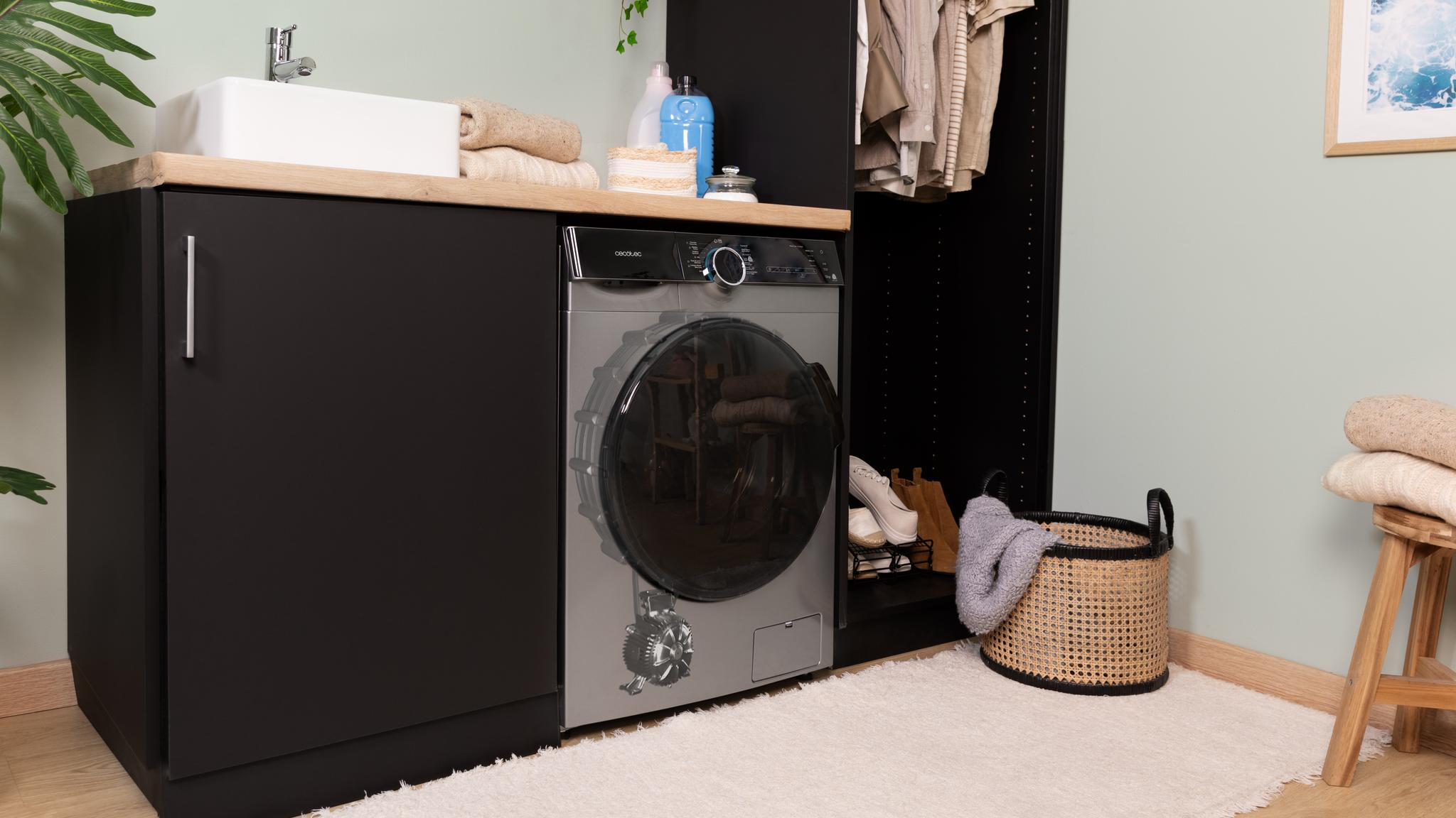 Lavadero: lavadora negra, lavabo, encimera de madera, ropa, alfombra, cesta, planta verde.