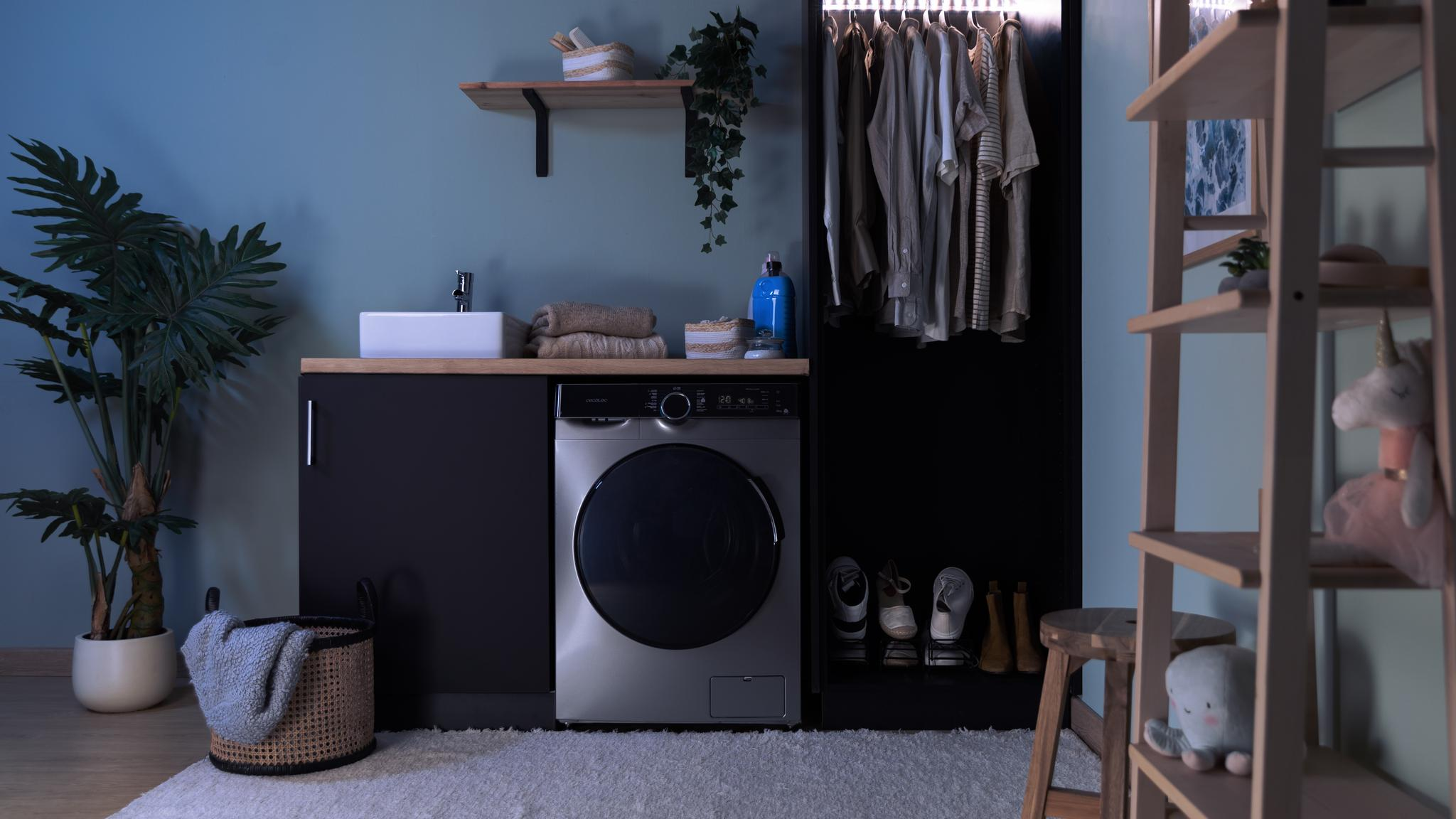 Un área de lavandería con lavadora, lavabo, estantes y ropa colgando de una barra.