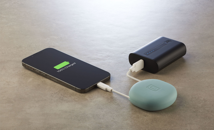 Telefon wird geladen. Das Telefon ist mit einer Powerbank und einem Ladepad verbunden. Telefon zeigt 100 % geladen.
