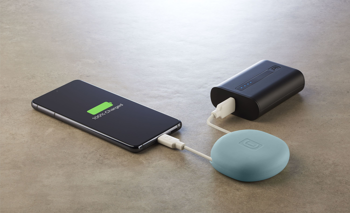 Smartphone, das von einer Powerbank aufgeladen wird, und ein kleiner, blauer Pod.