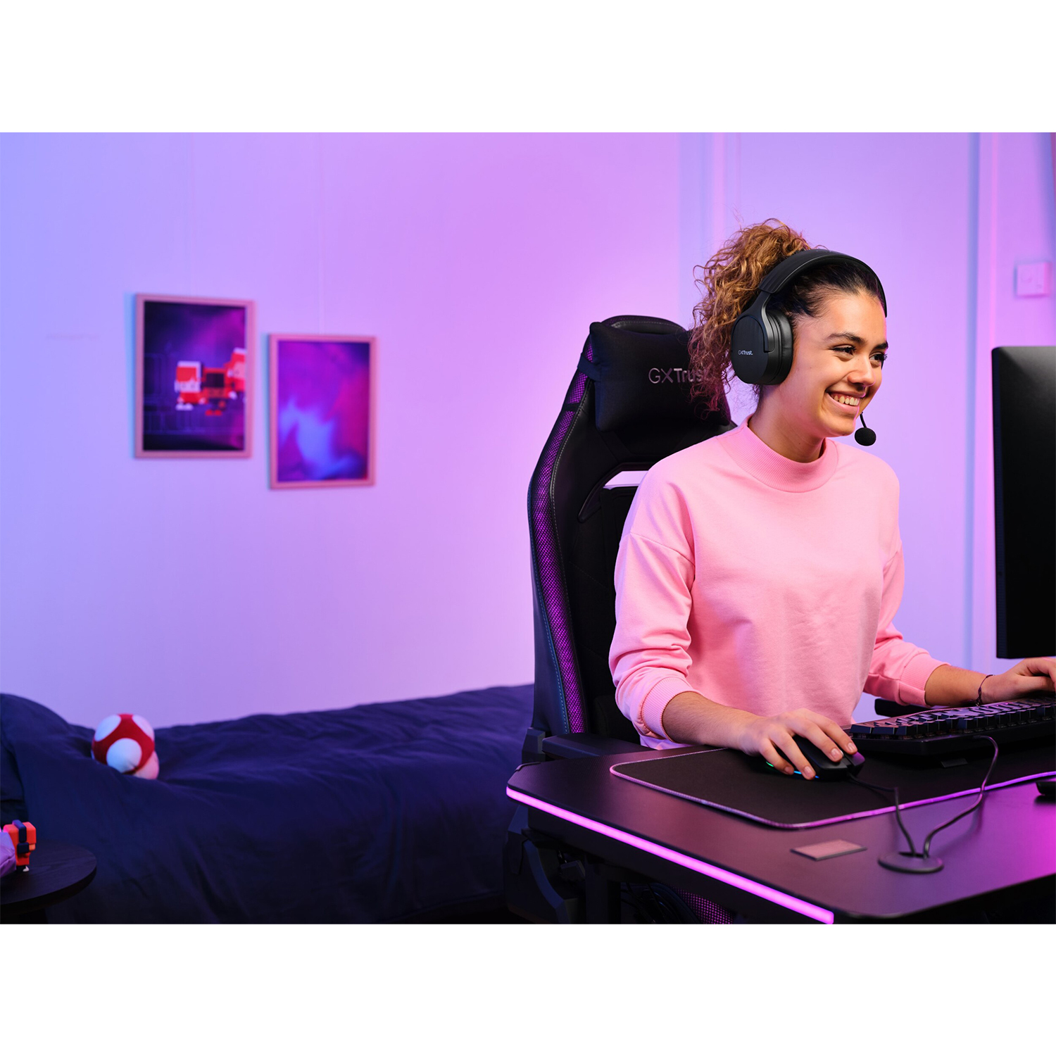 Donna con cuffie, gioca al computer con luci rosa e viola.