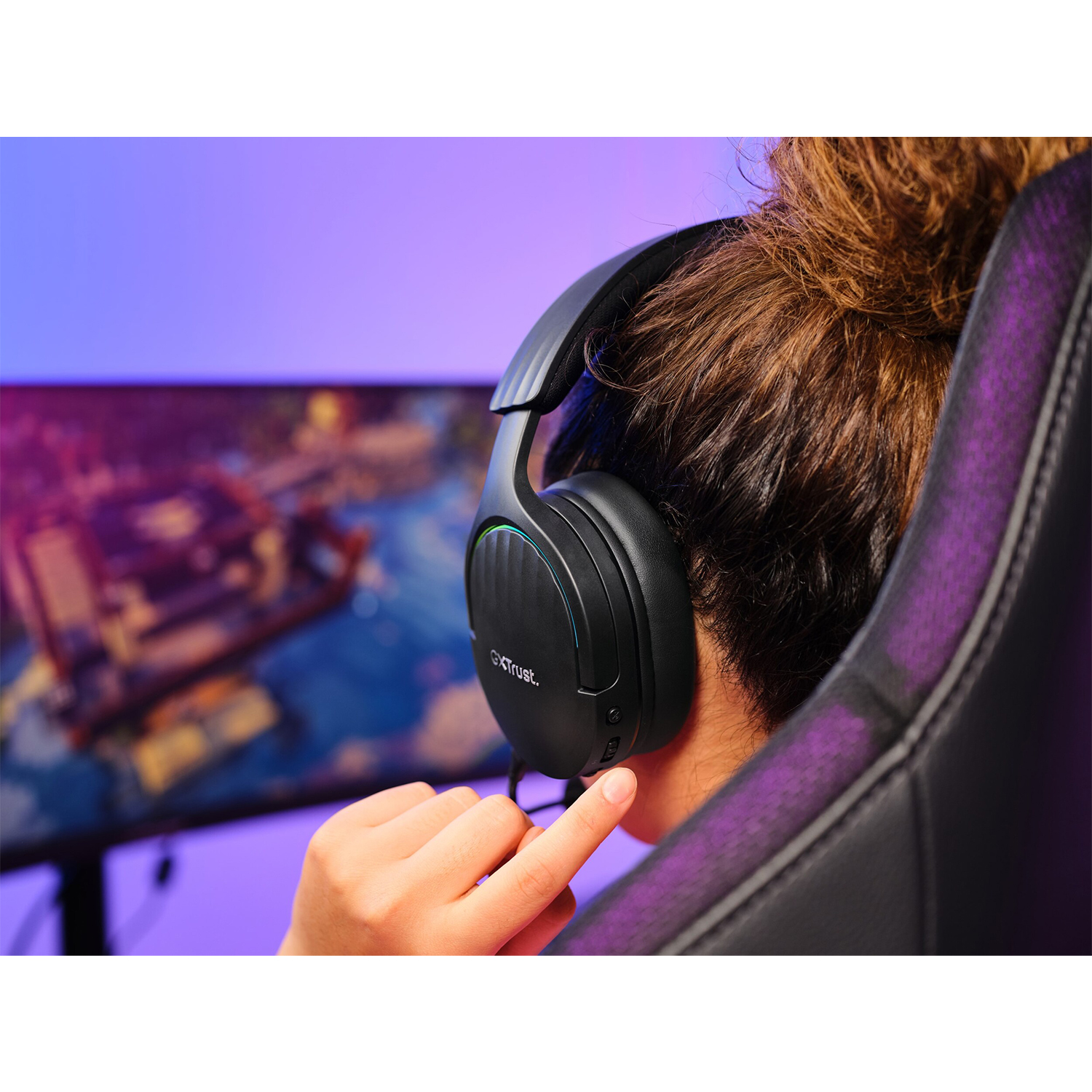 Persona con cuffie da gioco, guarda un monitor.
