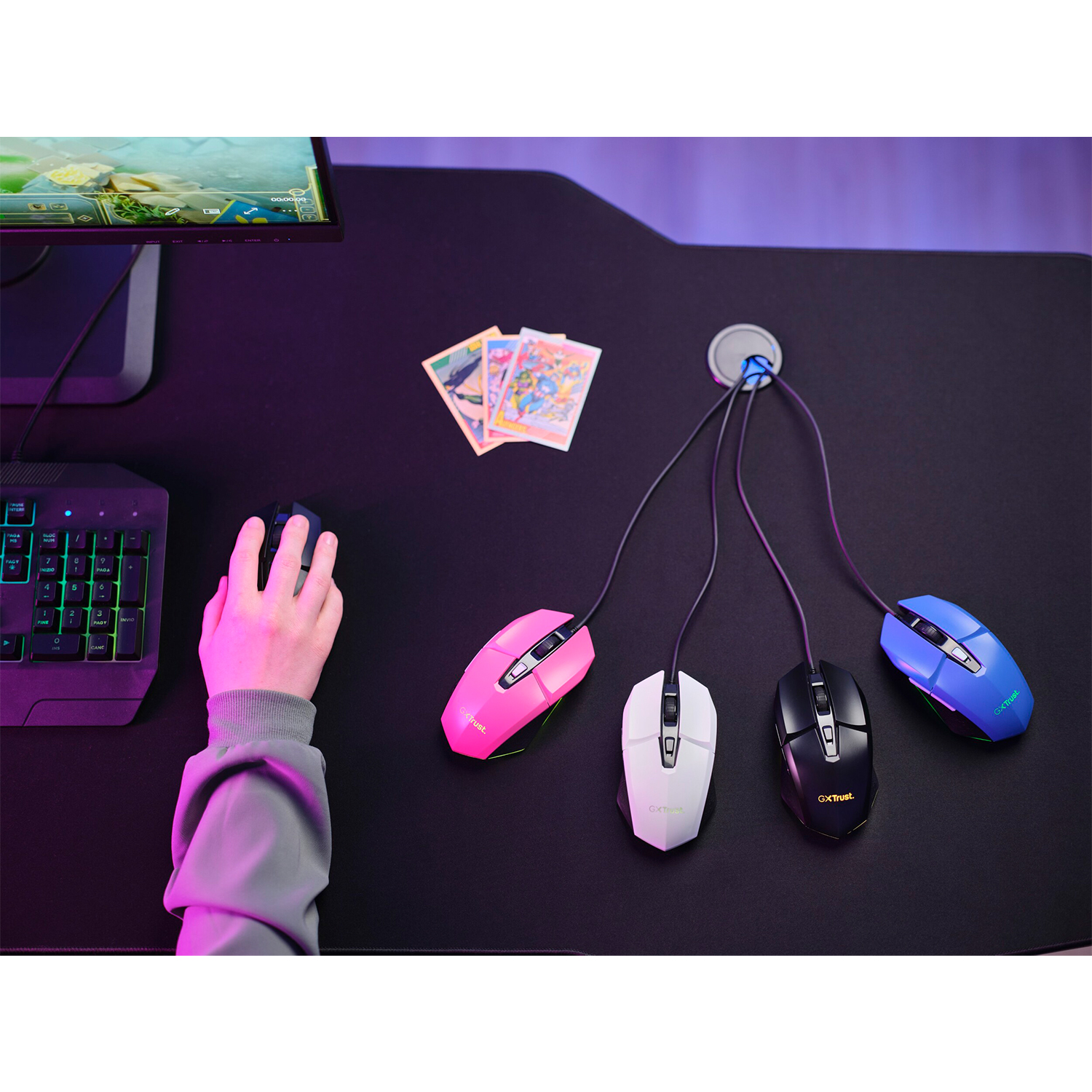 Mano raggiunge un mouse blu, quattro mouse su scrivania nera. Tastiera a sinistra.