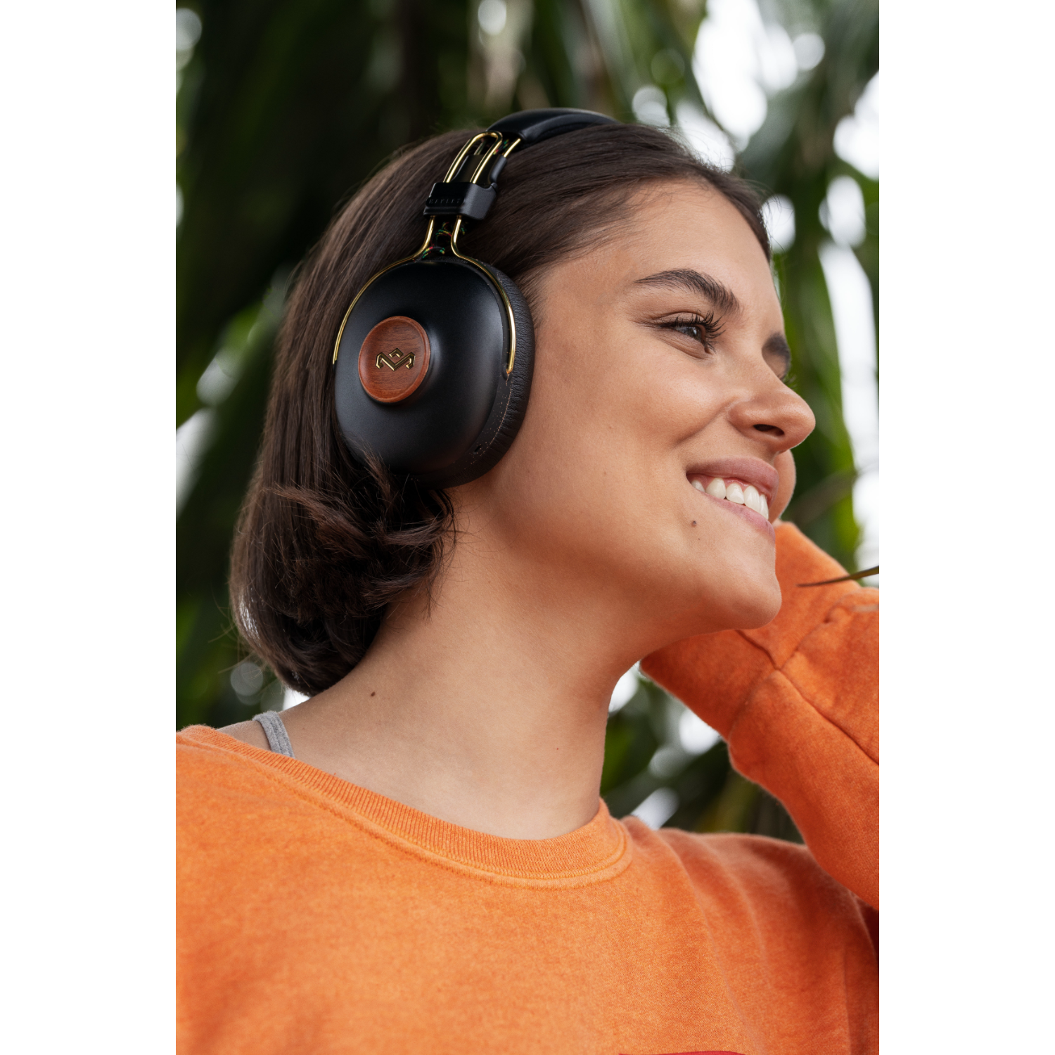 Woman with headphones smiling, blurred background.