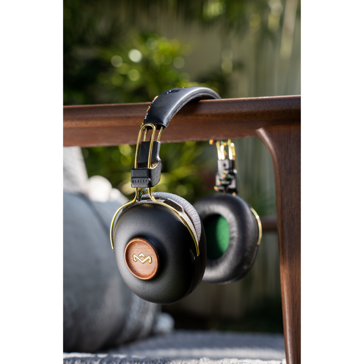 Black and gold headphones hanging on a wooden chair.