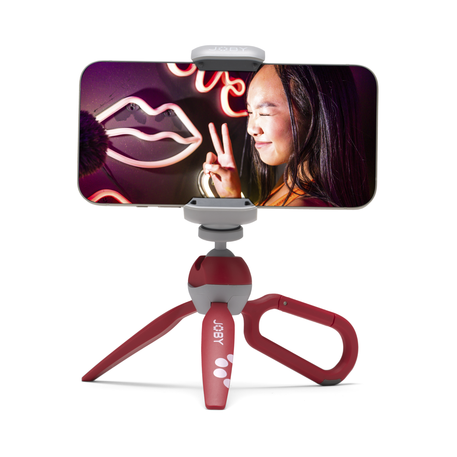 Persoon houdt telefoon op statief, selfie met neonlippen en vredesteken.