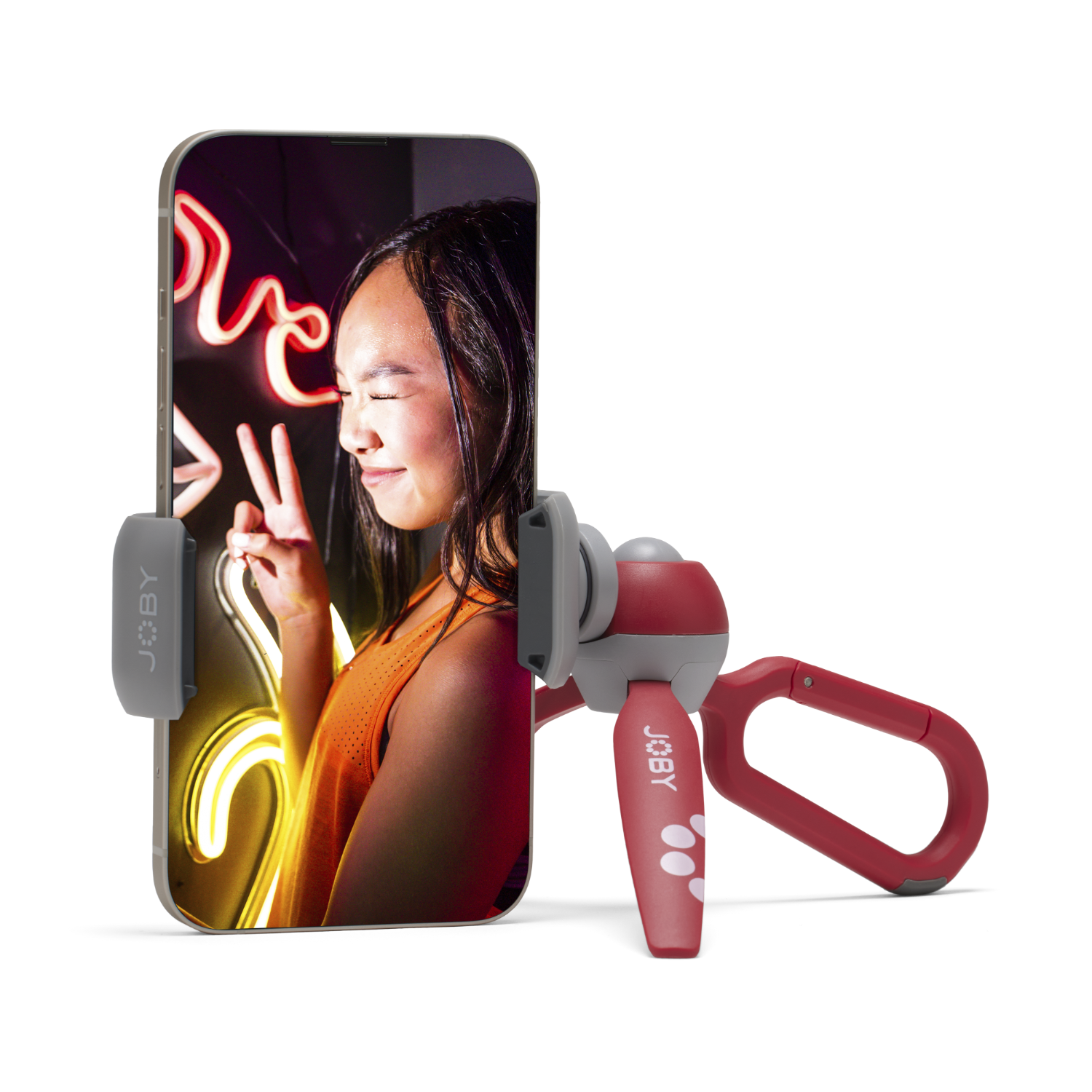 Een vrouw houdt een telefoon vast, bevestigd aan een statief. Neonreclame op de achtergrond.