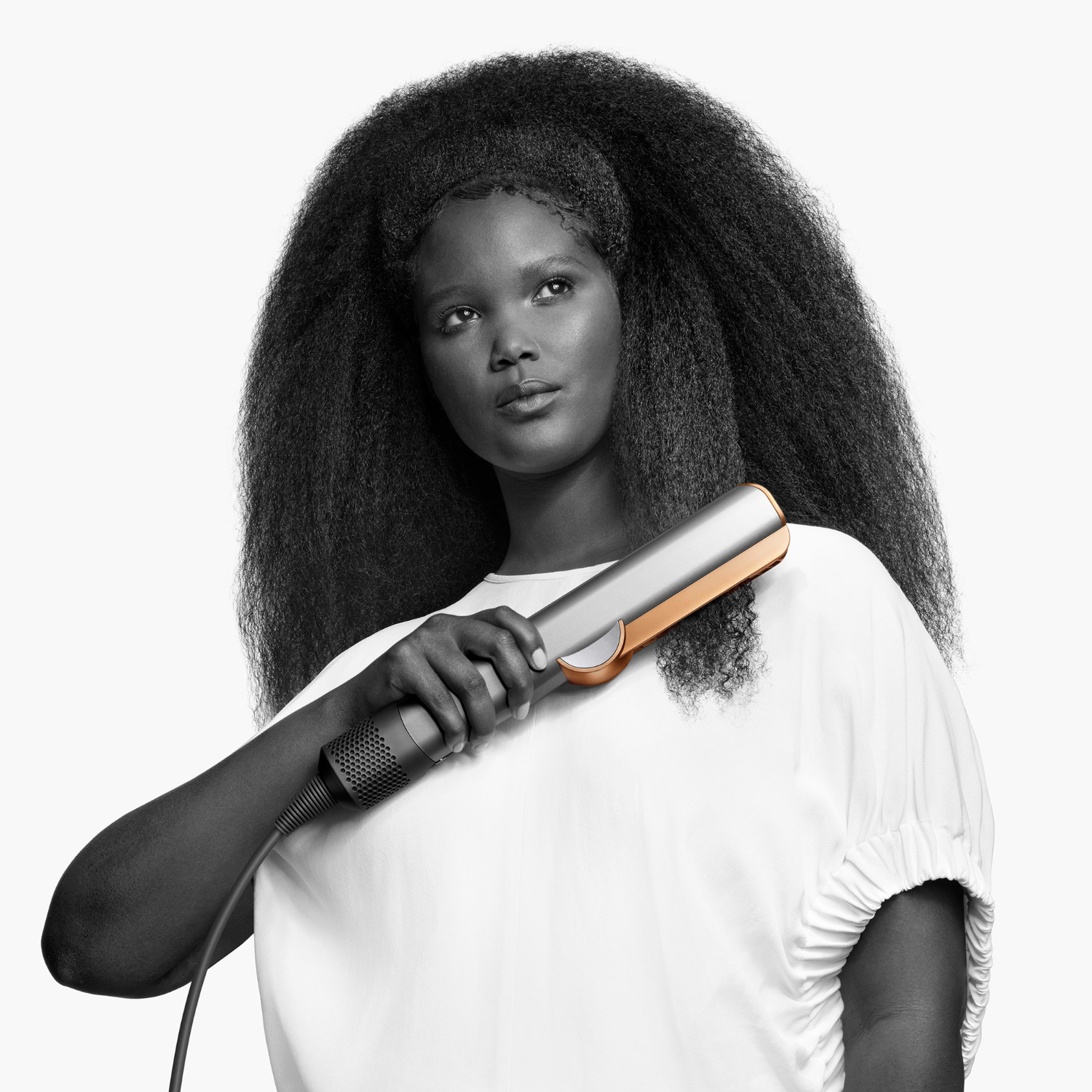 Black and white portrait of a woman holding a hair straightener.