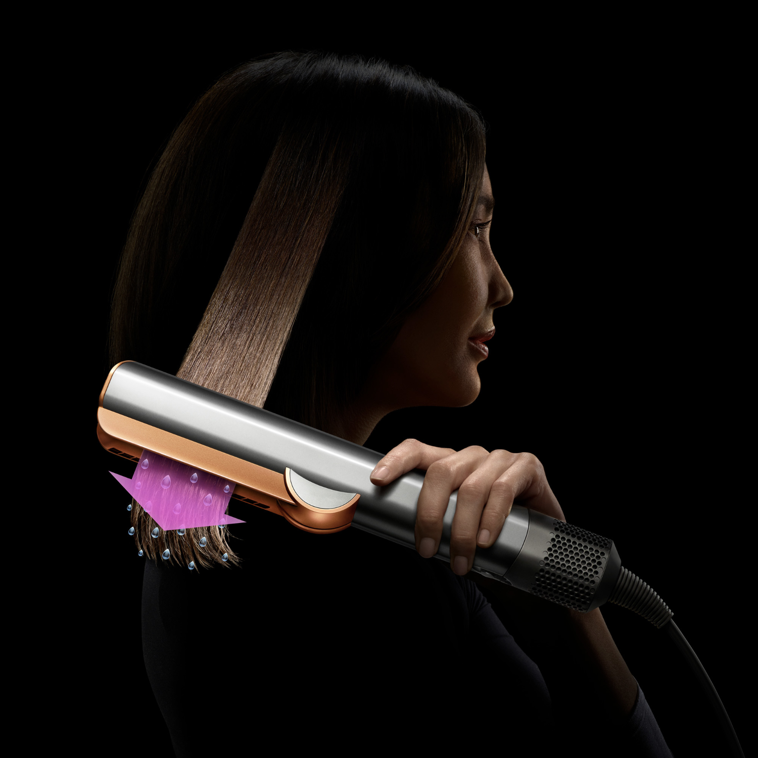 Person styling hair with a silver and copper hair straightener.