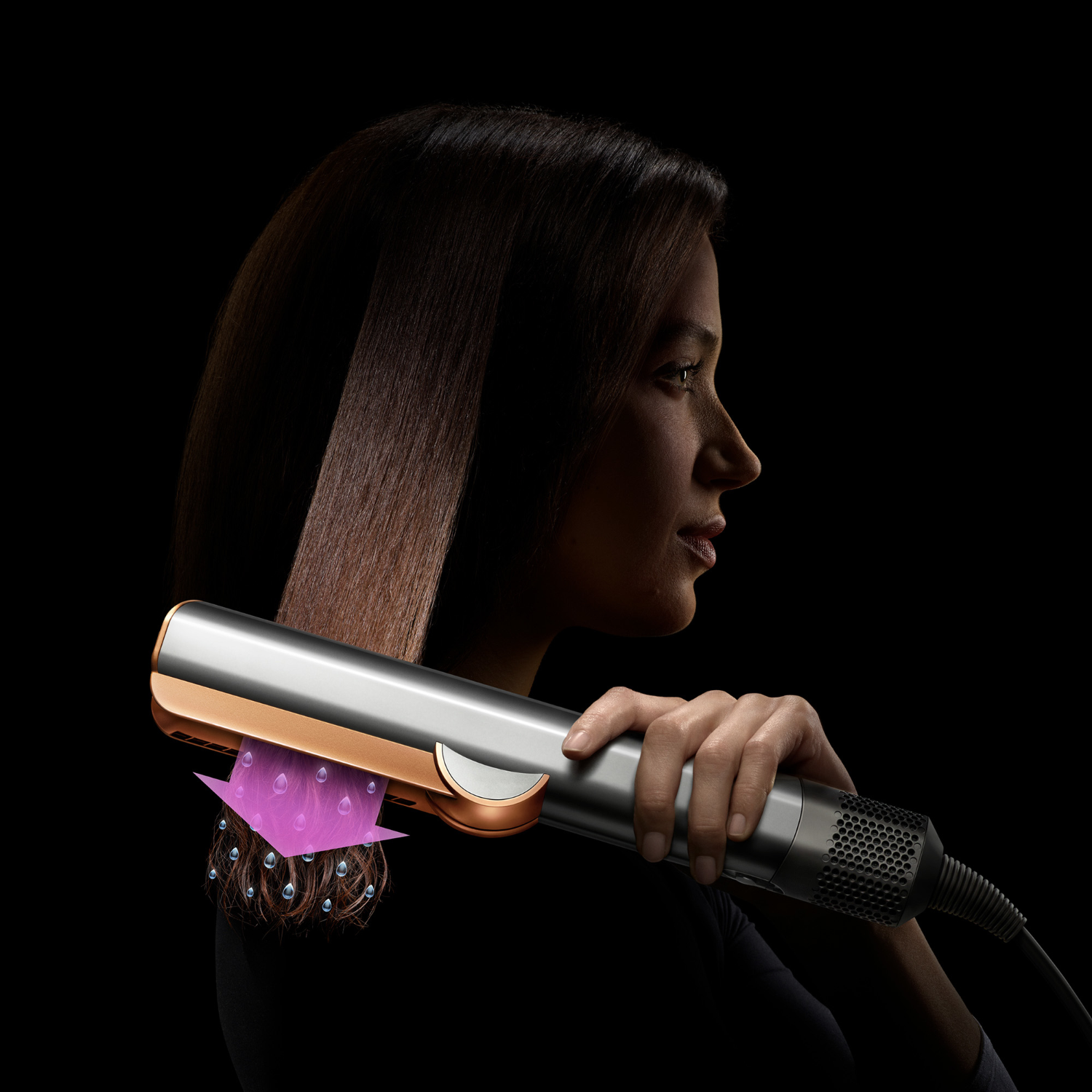 Woman using a hair straightener. Hair is being straightened. Black background.
