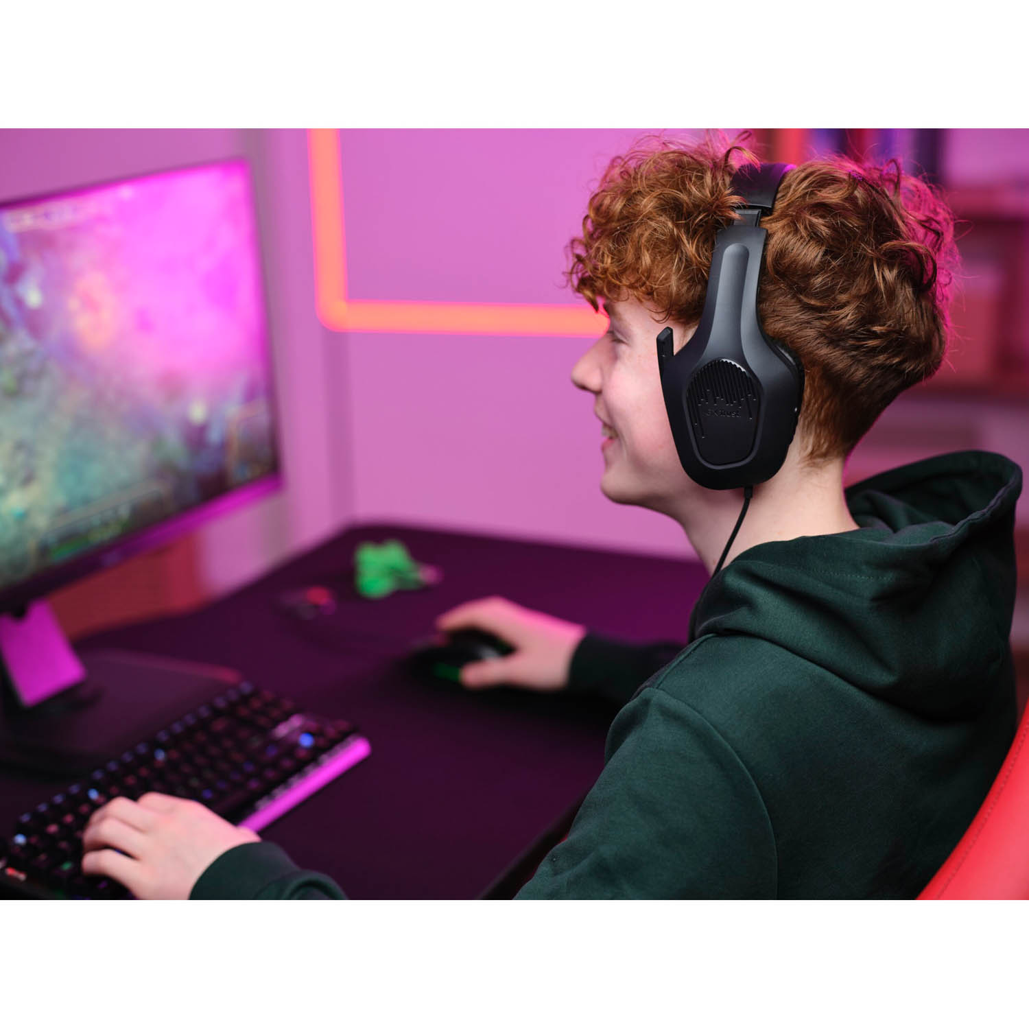 Adolescente con cuffie, gioca a un gioco al computer, sorride.