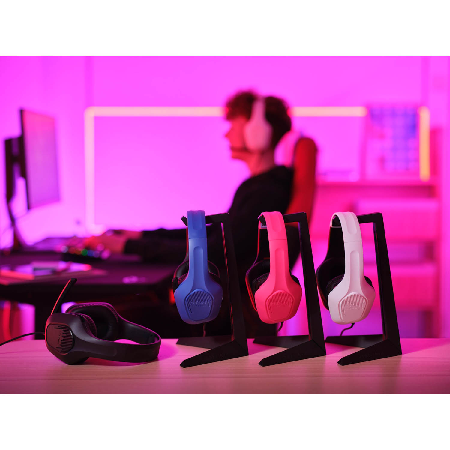 Cuffie su supporti. Una persona con le cuffie è seduta davanti a un computer.