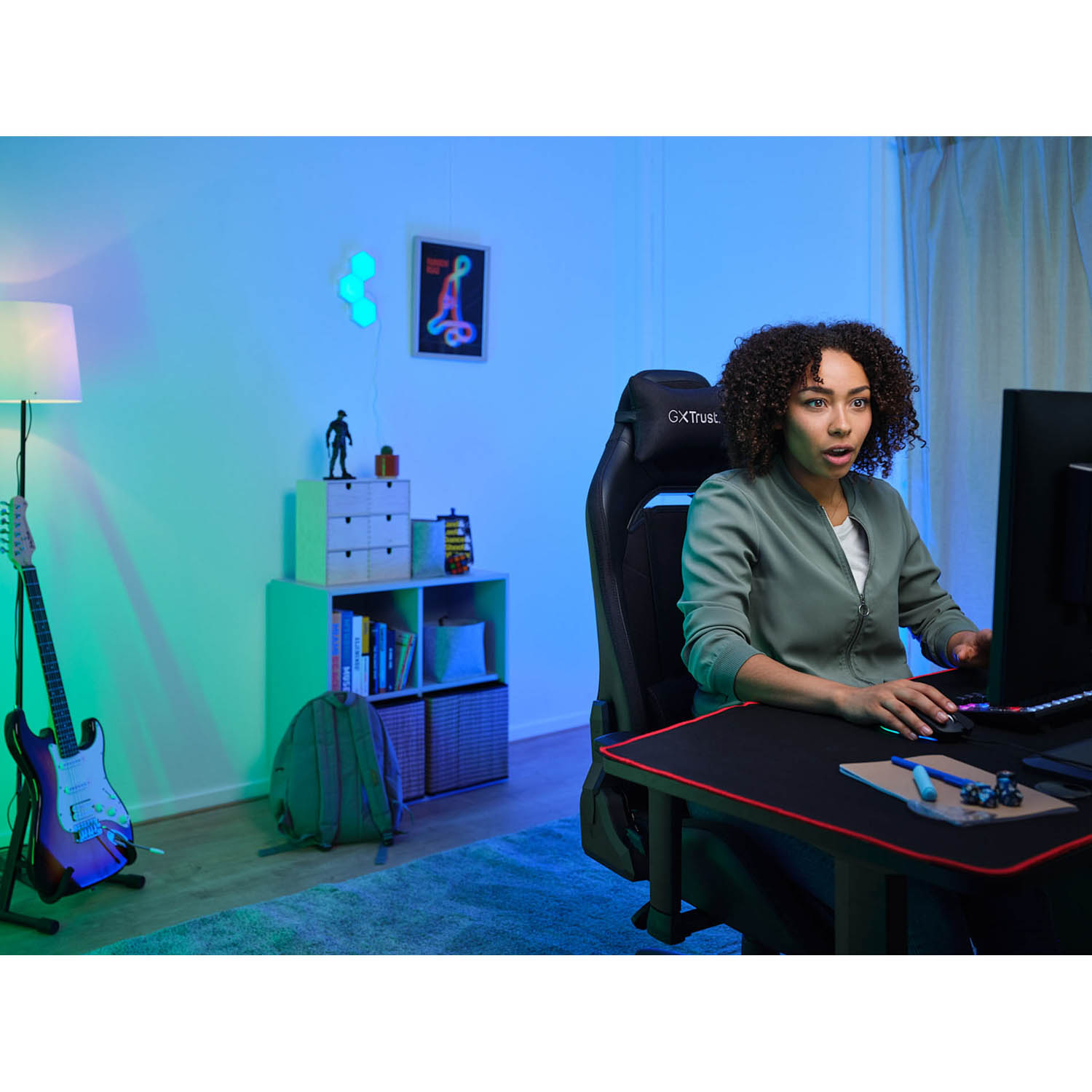 Una donna su una sedia da gioco guarda lo schermo di un computer in una stanza con configurazione da gioco.