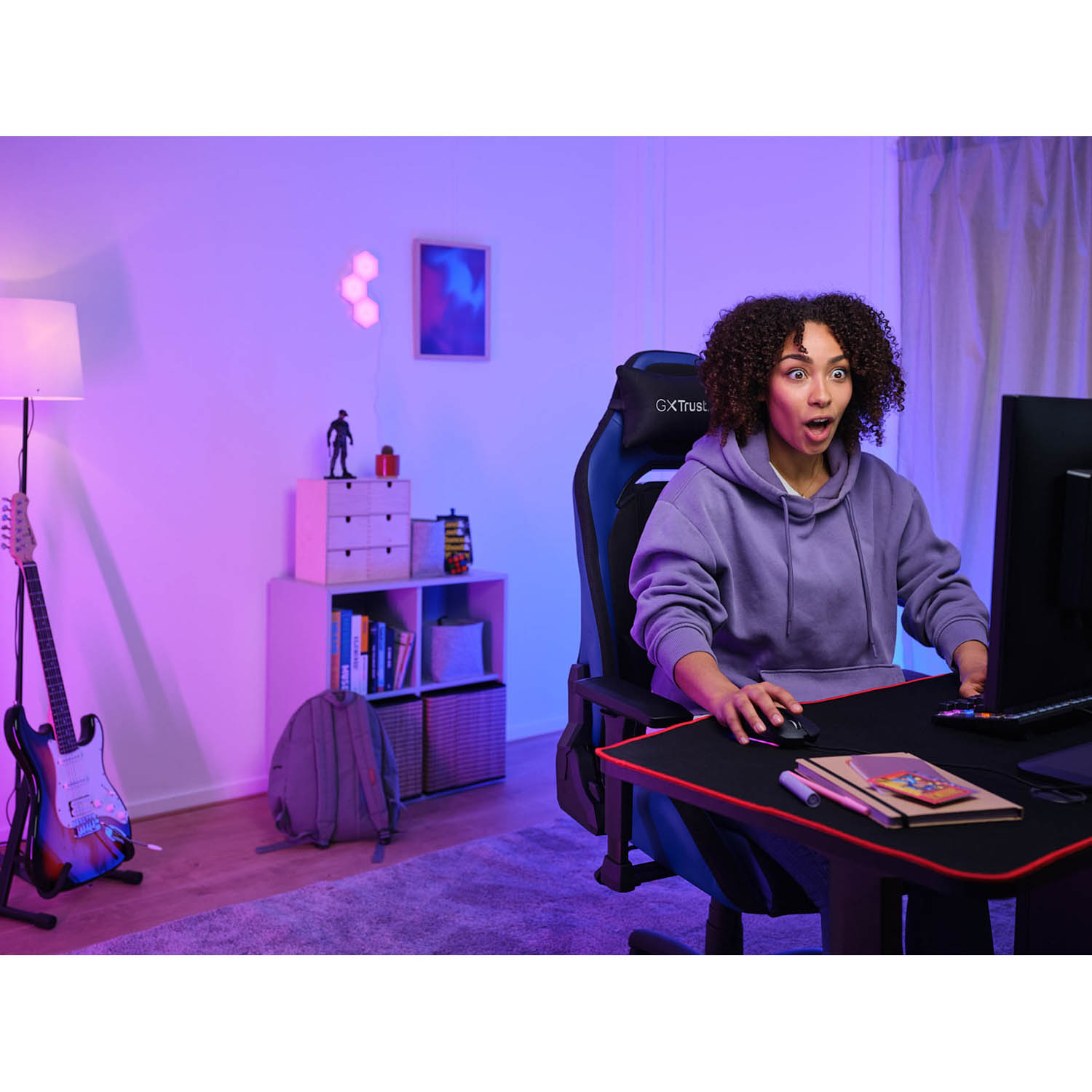 Donna che gioca con espressione sorpresa in una stanza con illuminazione viola e rosa.