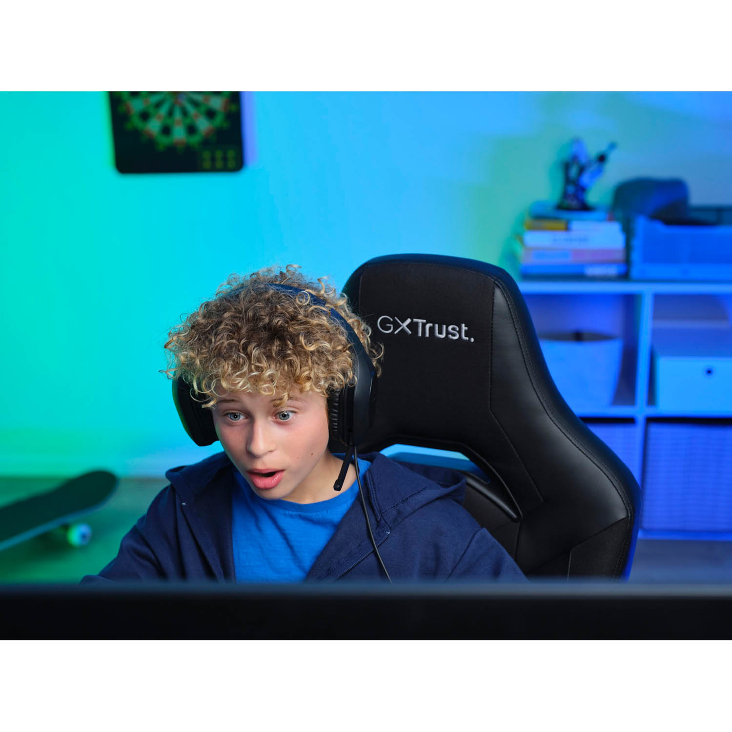 Giovane gamer con cuffie, sorpreso. Seduto su una sedia da gaming, schermo davanti.