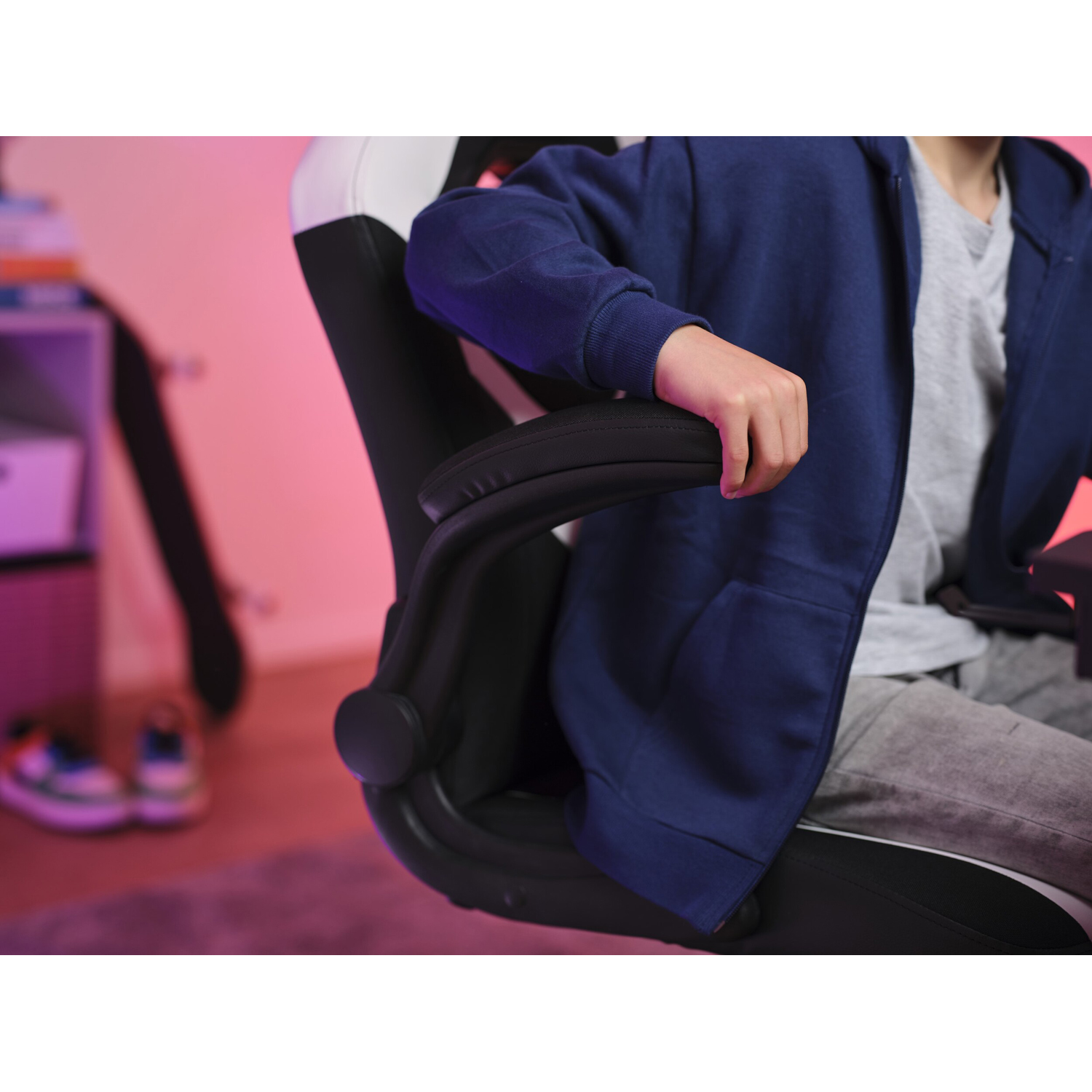 Persona seduta su una sedia da gaming, bracciolo visibile, stanza con illuminazione rosa.