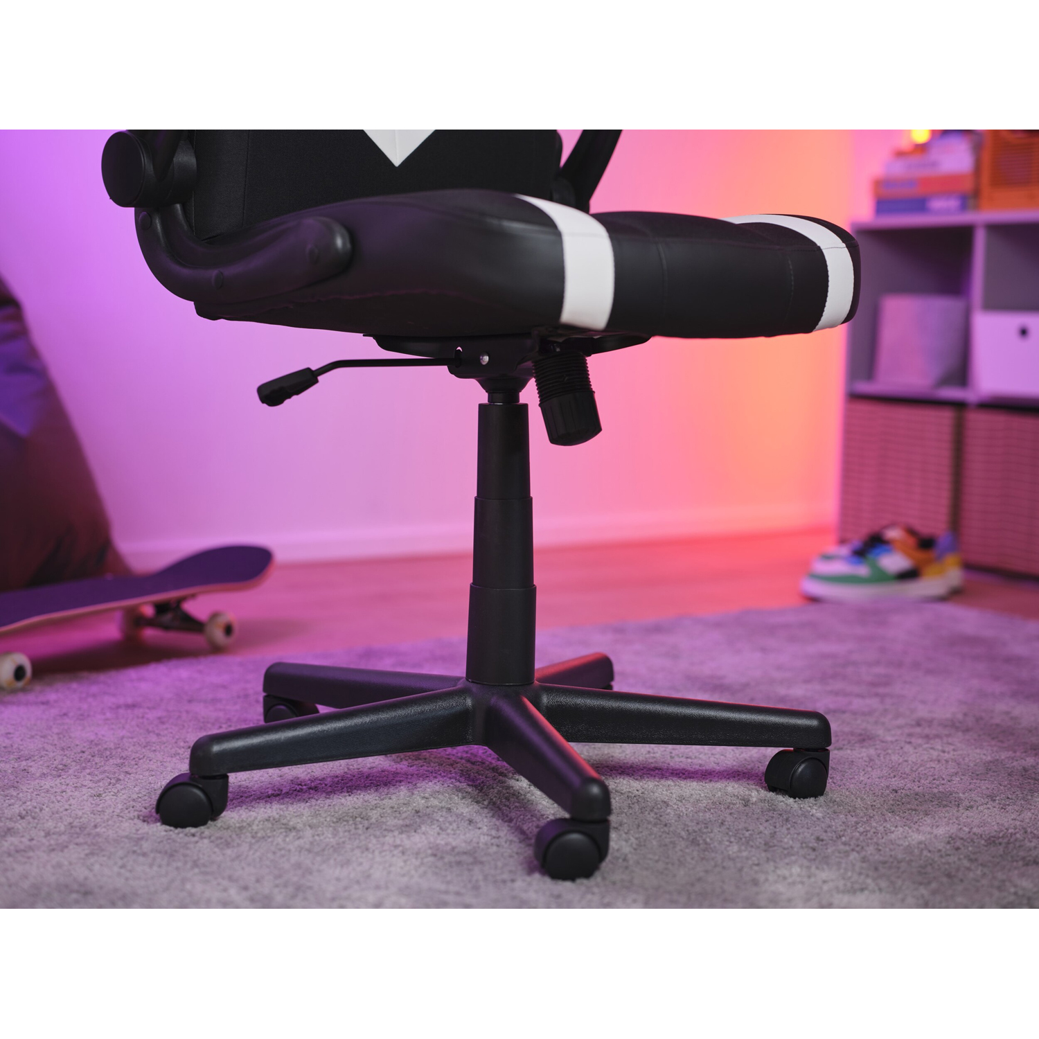 Sedia da gaming bianca e nera con ruote. Sfondo: skateboard, scarpe da ginnastica e scaffali.