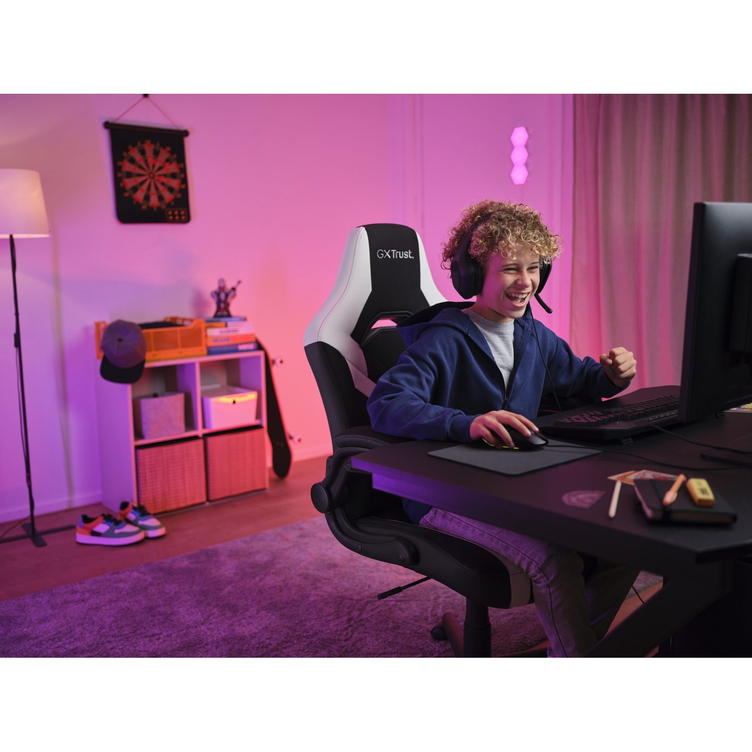 Ragazzo che gioca al computer, sorridendo con le cuffie.