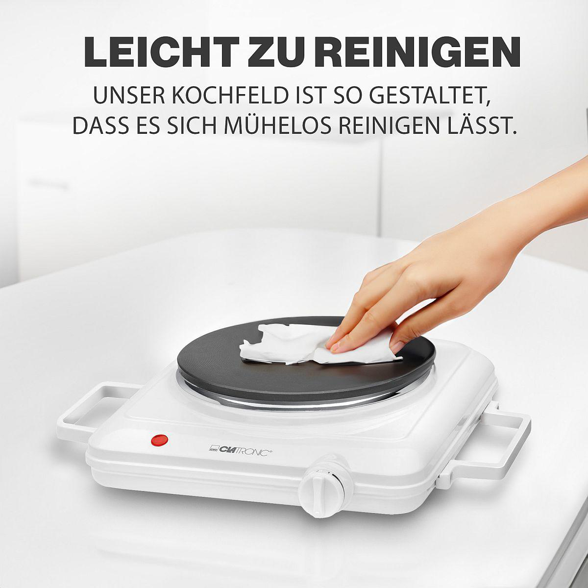 Eine Hand wischt mit einem weißen Tuch über eine schwarze elektrische Kochplatte.