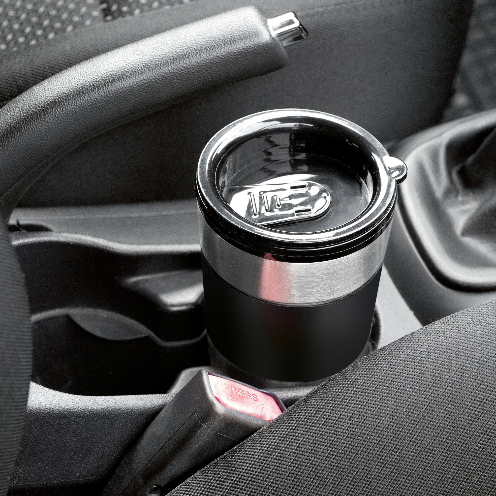 Getränkehalter im Auto mit einem schwarzen und silbernen isolierten Reisebecher und roter Gurtschnalle.